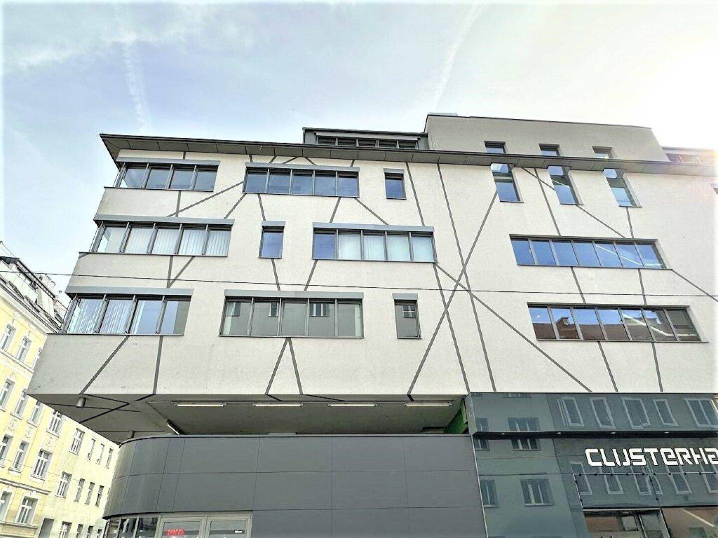 Moderne Gebäudefassade mit markanten geometrischen Linien und vielen Fenstern unter blauem Himmel.