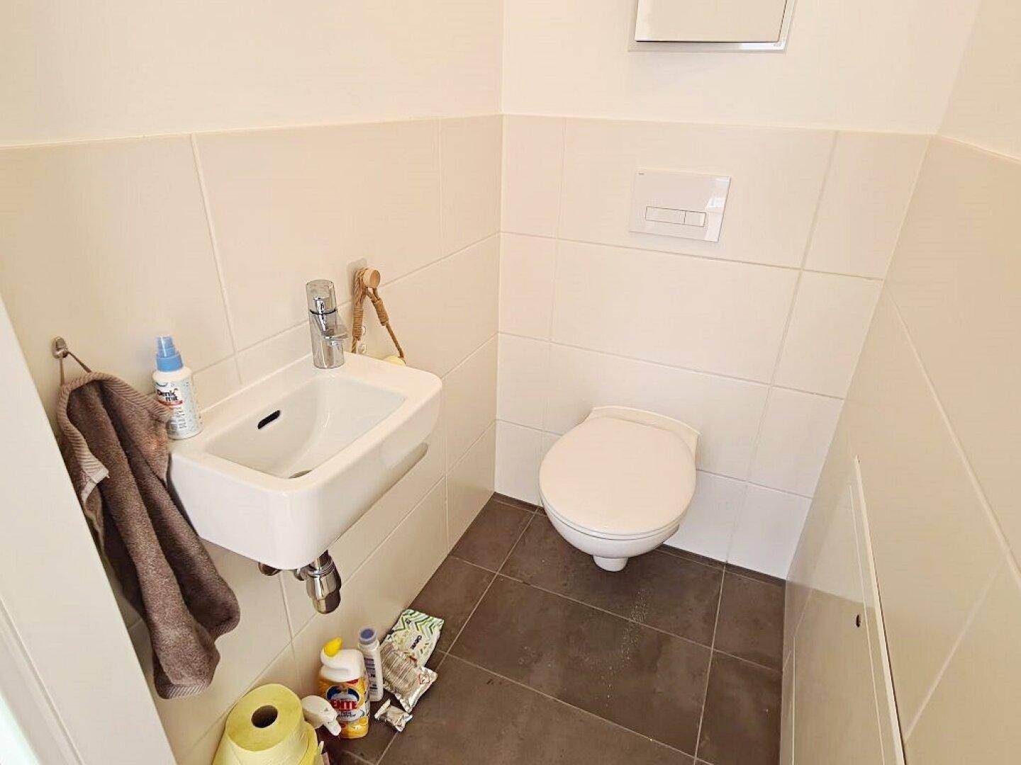 Kleines Gäste-WC mit wandhängender Toilette und kompaktem Waschbecken, ideal für Besucher.