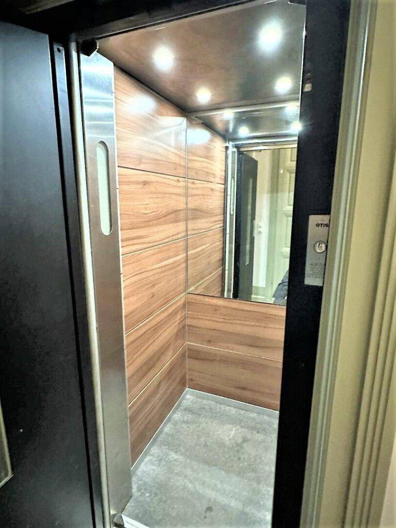 Moderner Aufzug mit stilvoller Holzverkleidung und einem robusten Bodenbelag für den täglichen Gebrauch.