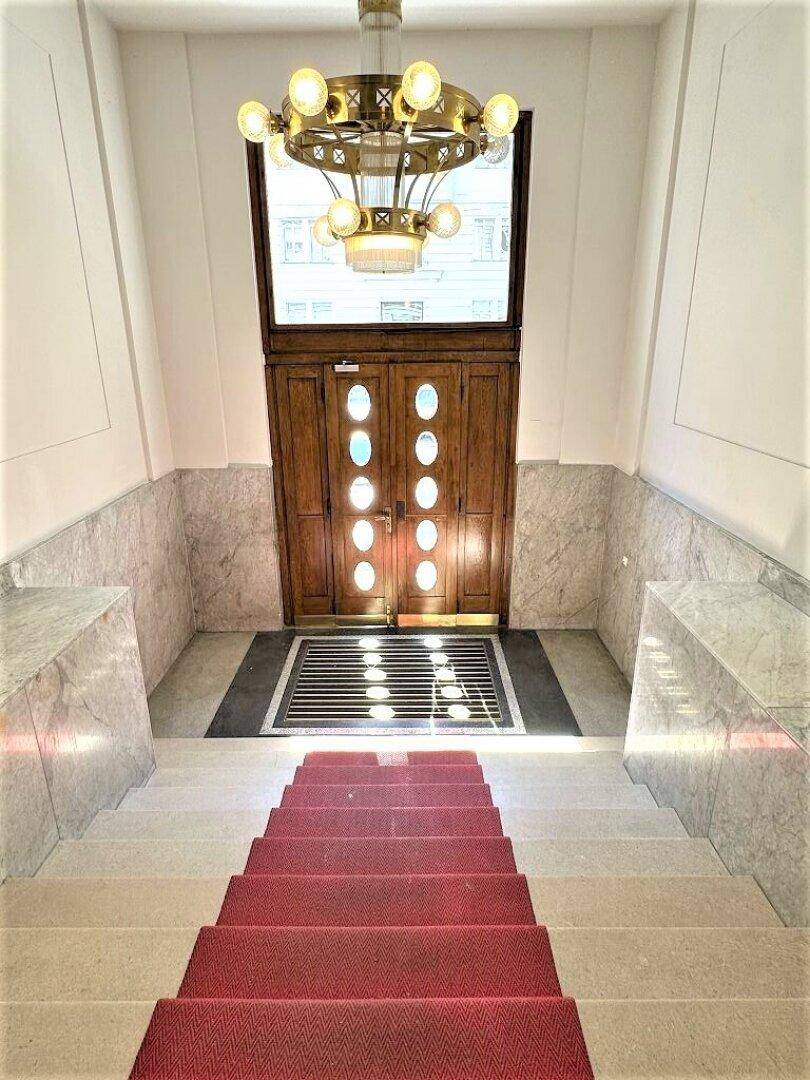 Der elegante Eingangsbereich besticht durch eine breite Treppe, Marmorwände und einen prunkvollen Kronleuchter.