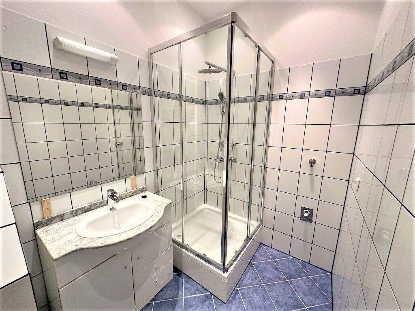 Modernes Badezimmer mit Eckdusche, Waschbecken und hellen Fliesen.