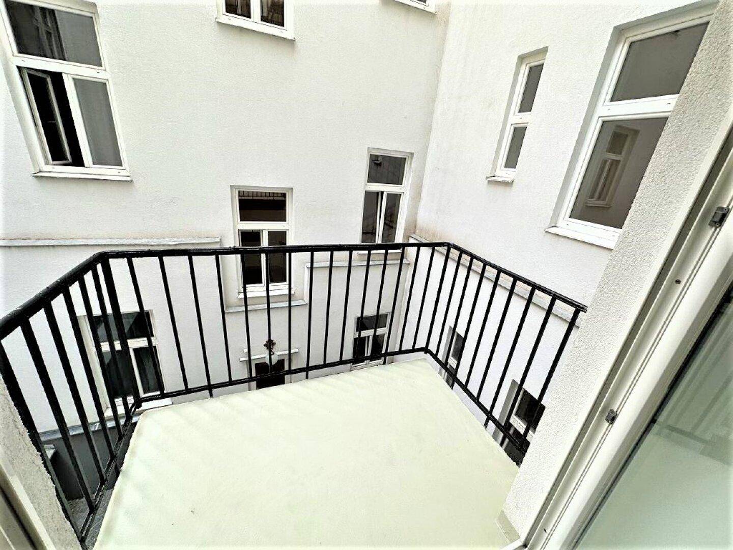 Blick vom Balkon auf den Innenhof mit weiteren Fenstern und weißer Fassade.