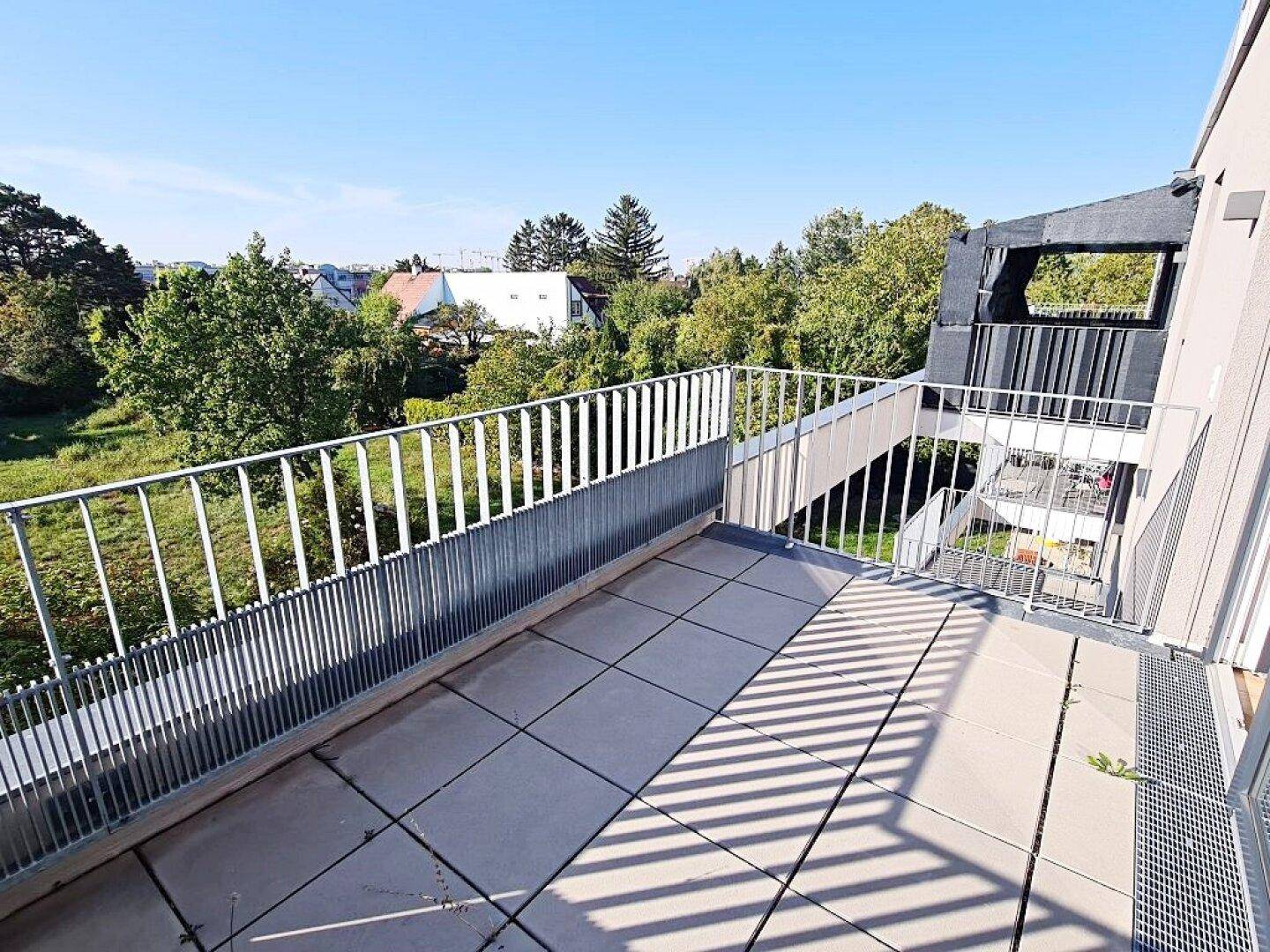 Heller Balkon mit Fliesenboden und Blick auf die Umgebung sowie die moderne Gebäudearchitektur.
