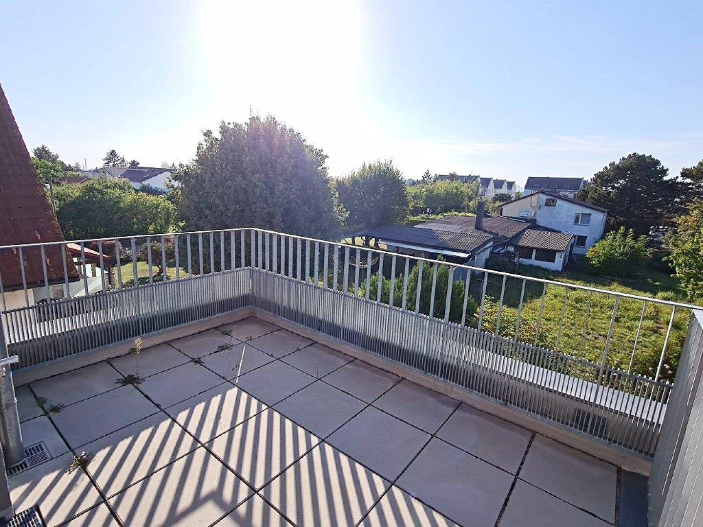 Großer Balkon mit Fliesen und Metallgeländer, der eine weite Aussicht ins Grüne bietet.