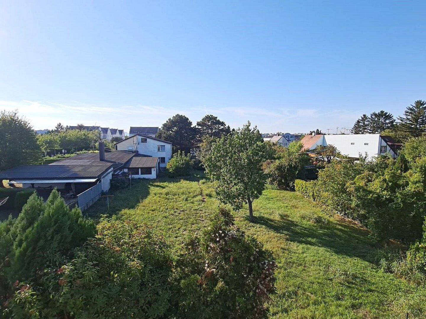 Weitläufiger Blick über grüne Gärten und die umliegende Wohnbebauung an einem sonnigen Tag.