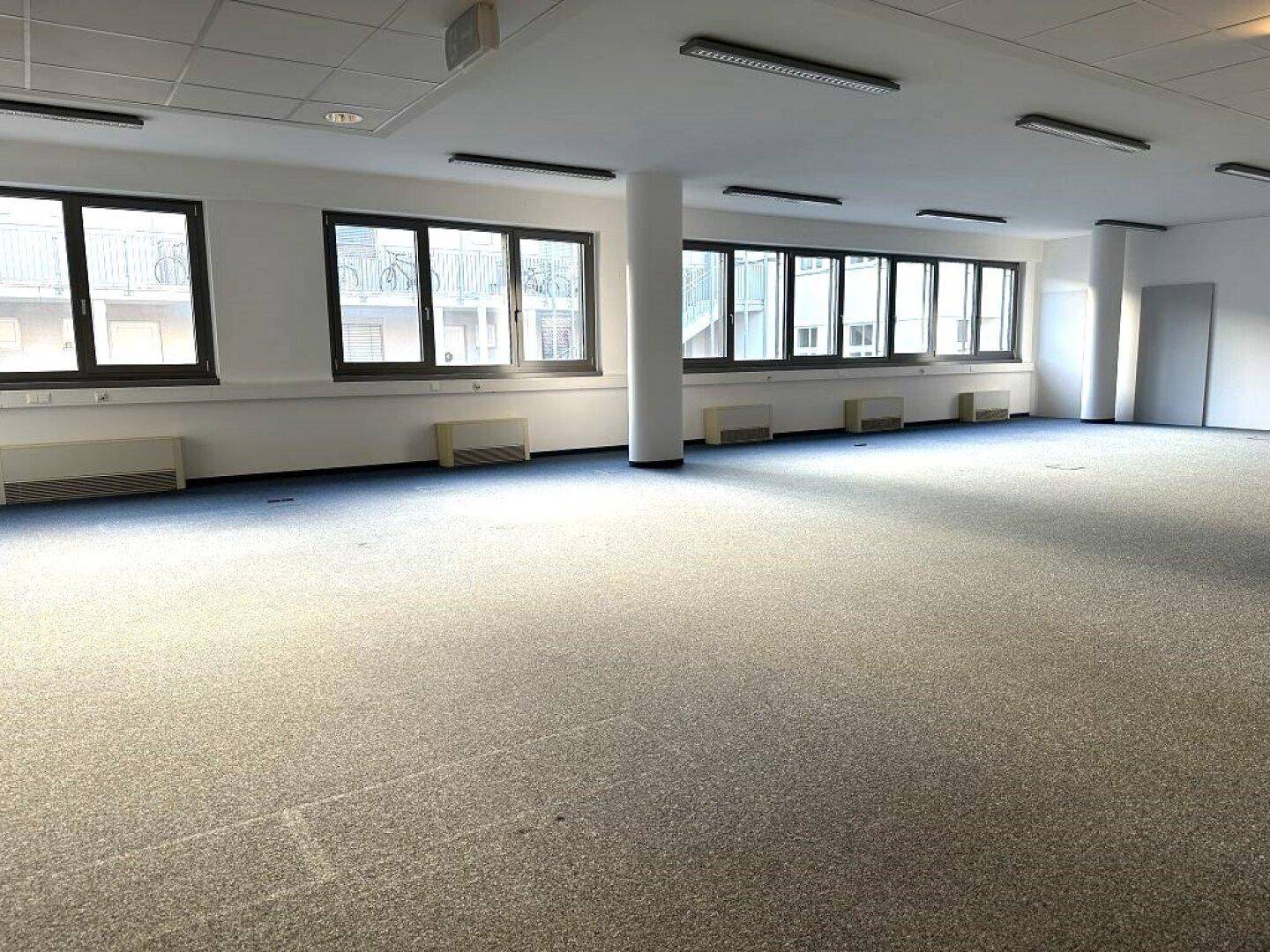 Weitläufiger Bürobereich mit vielen Fenstern, die viel Tageslicht hereinlassen, und einem Säulenakzent.