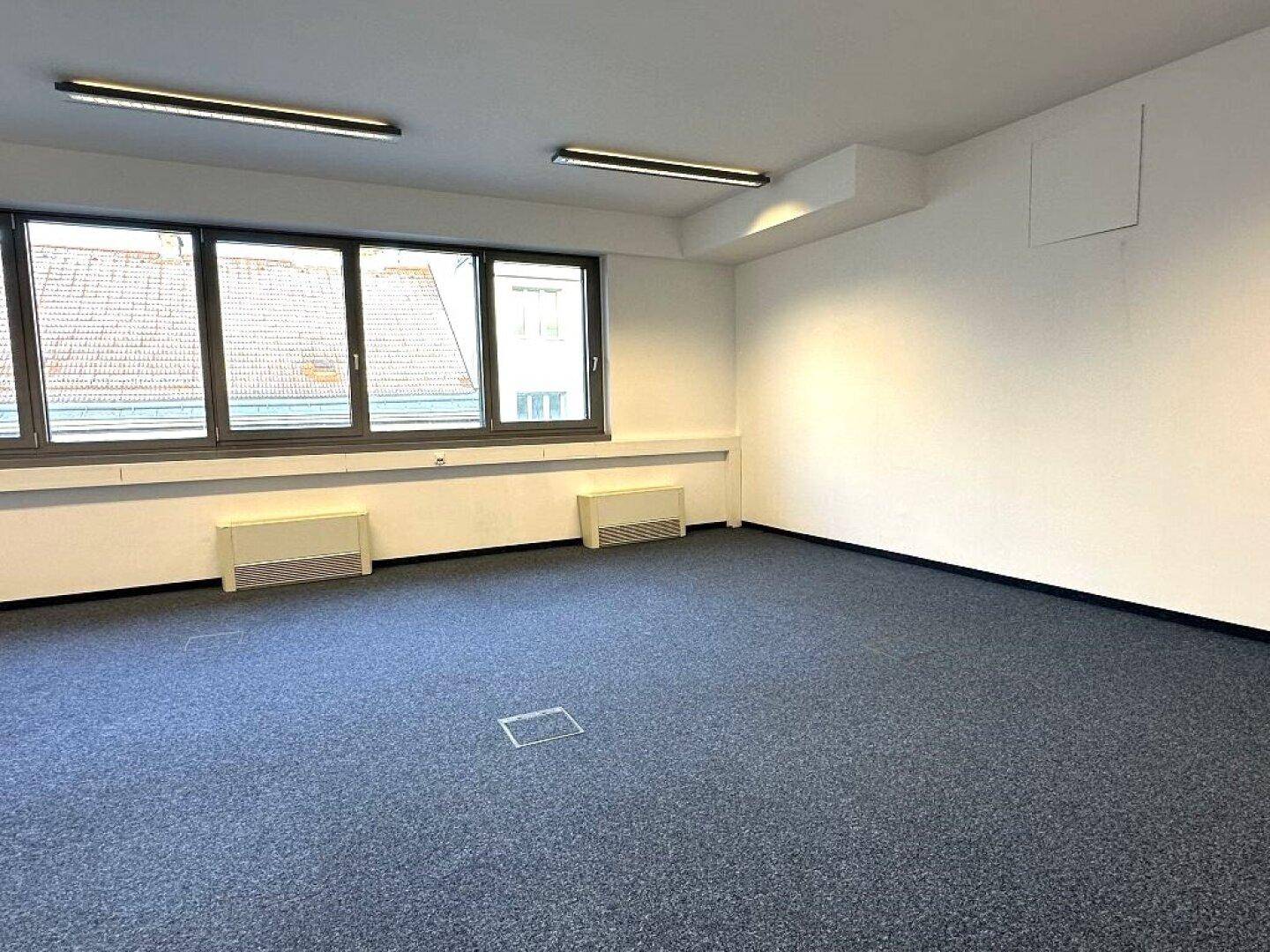 Geräumiger Büroraum mit Teppichboden und weißen Wänden, bietet viel Platz für individuelle Gestaltung.