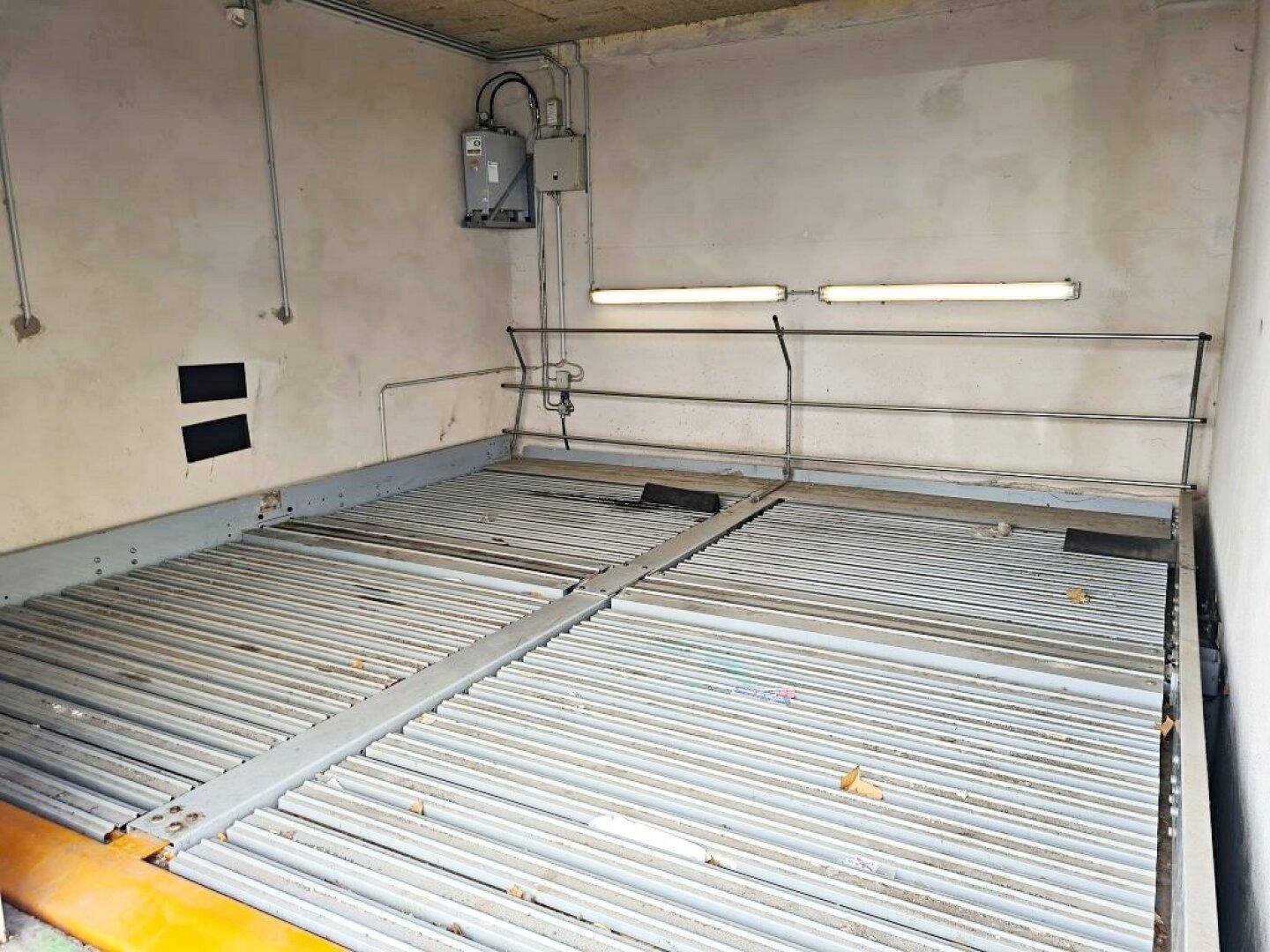 Innenansicht der Tiefgarage mit mechanischem Parksystem, Betonwänden und einfacher Beleuchtung.