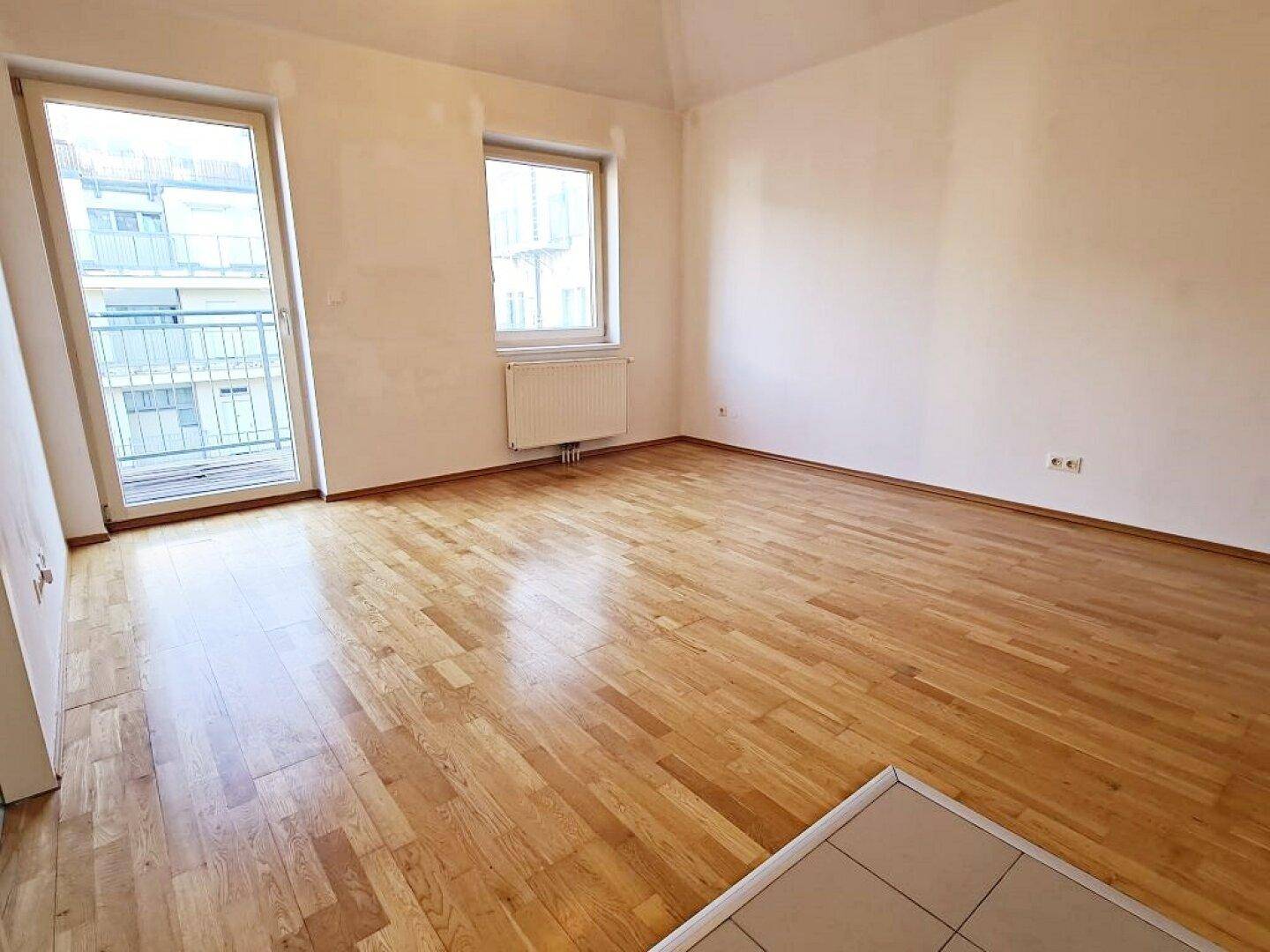 Lichtdurchflutetes Zimmer mit Parkettboden und Balkonzugang, bietet eine angenehme Wohnatmosphäre.
