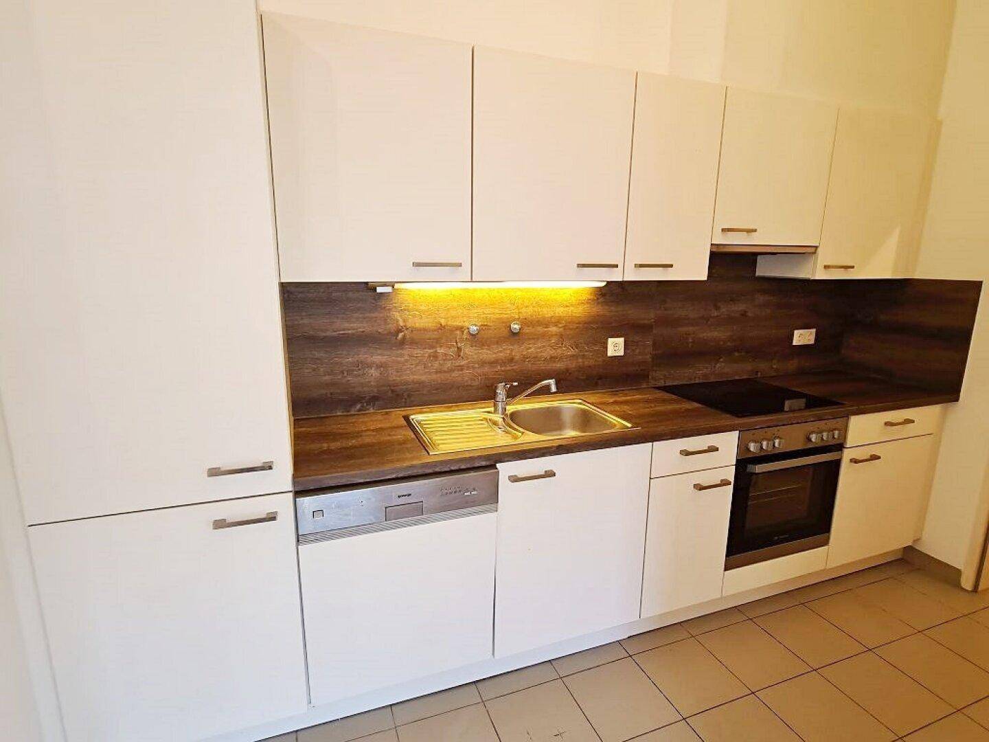 Moderne Einbauküche mit weißen Schränken, Holzarbeitsplatte und integrierten Geräten.