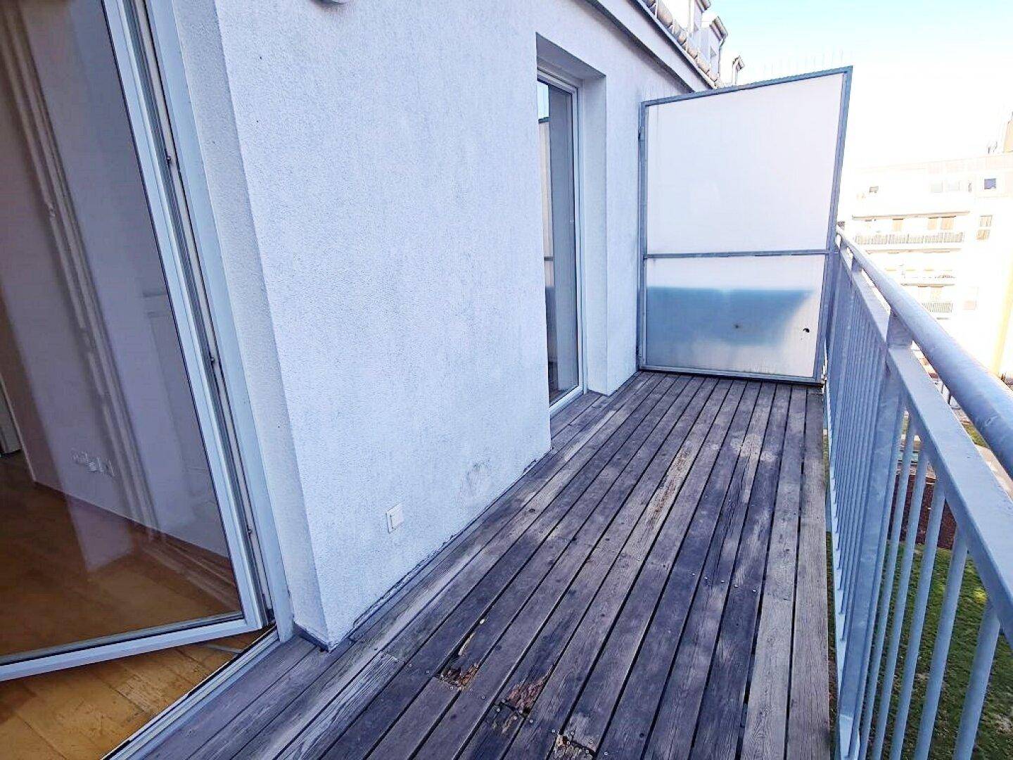 Geräumiger Balkon mit Holzdielen und Metallgeländer, bietet Platz für Entspannung im Freien.