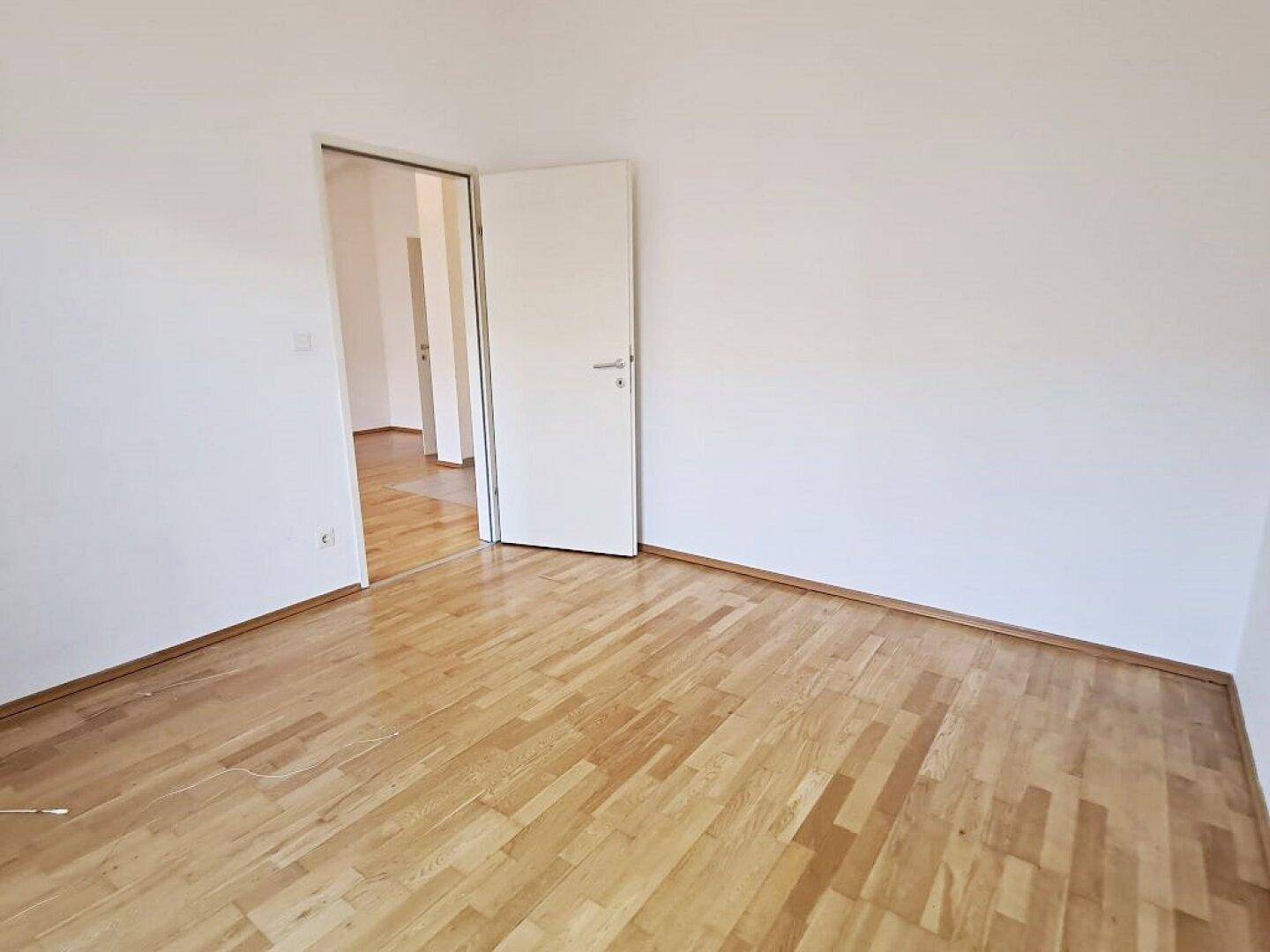Helles Zimmer mit Parkettboden und weiß gestrichenen Wänden, bietet vielseitige Nutzungsmöglichkeiten.
