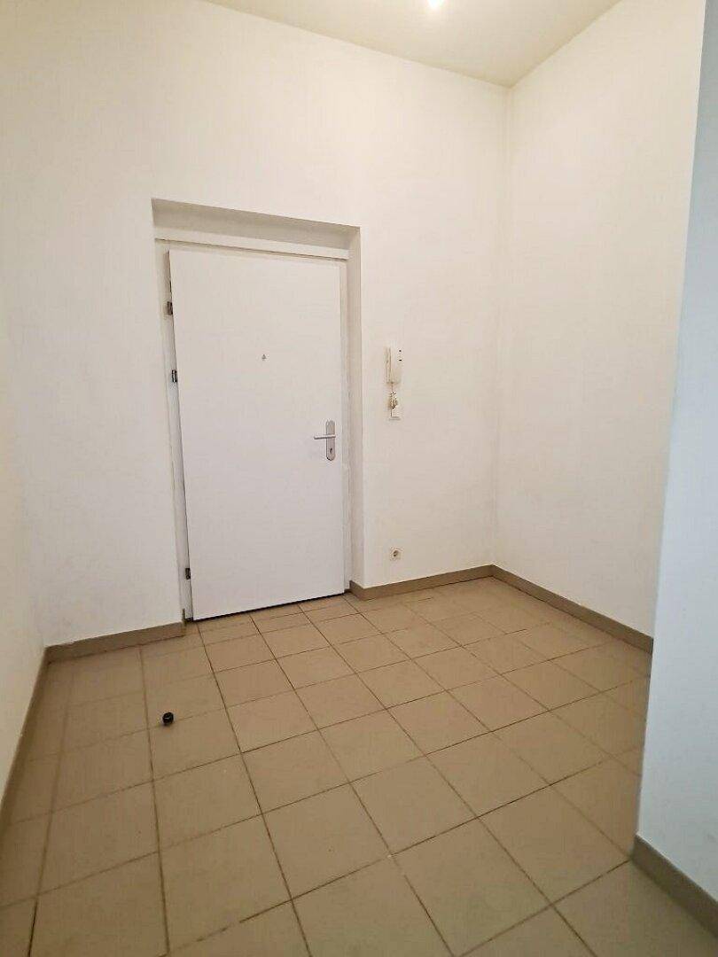 Eingangsbereich mit Fliesenboden und weißer Eingangstür, bietet Zugang zu weiteren Räumen.