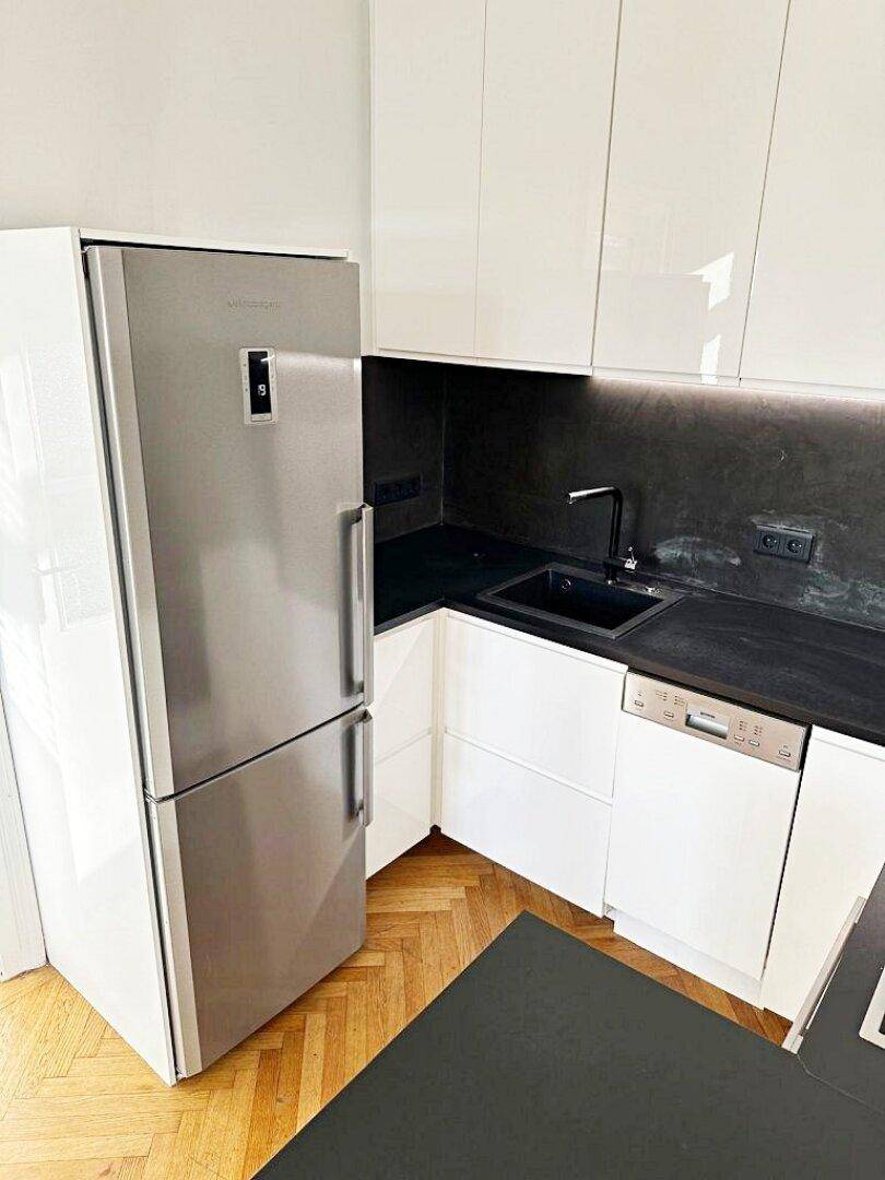 Ansicht der Küche mit Edelstahlkühlschrank, Spüle und integriertem Geschirrspüler.