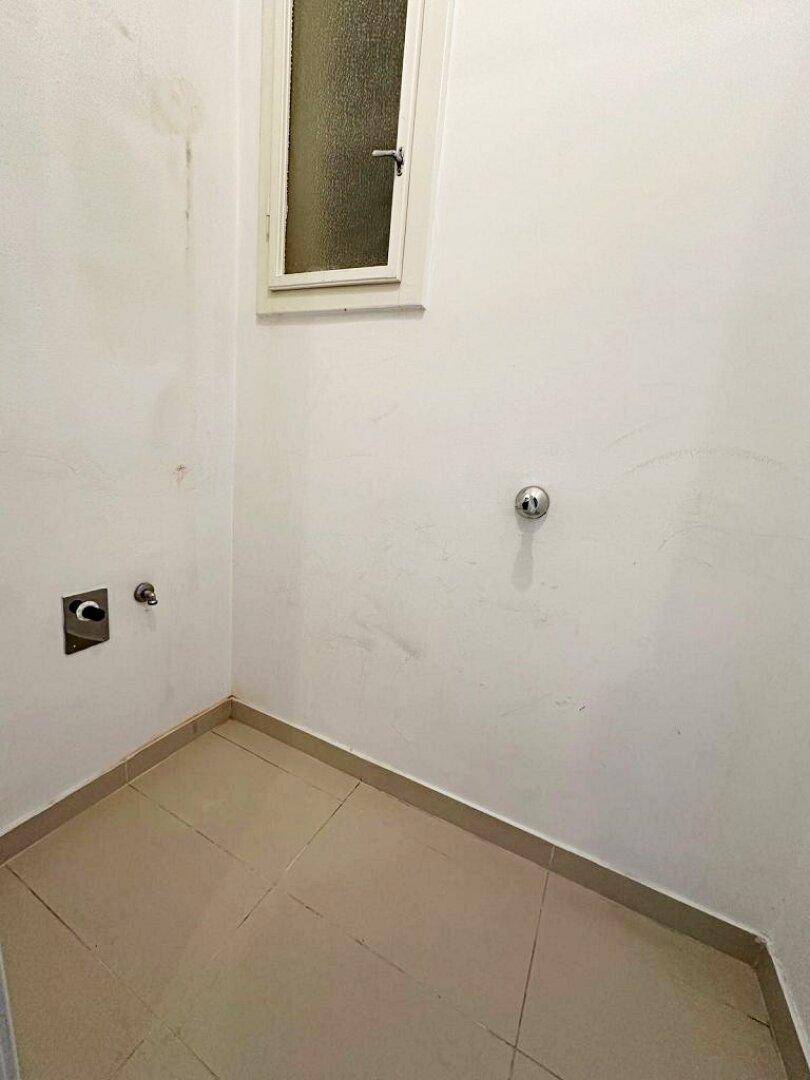 Kleiner Hauswirtschaftsraum mit Fenster und Anschlüssen für Waschmaschine oder Spüle.
