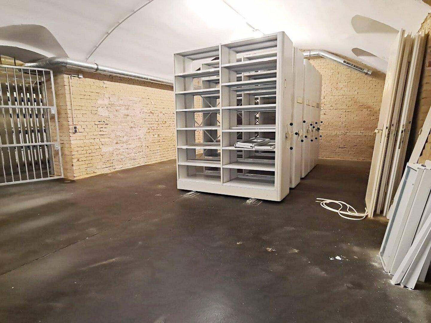 Kellerraum mit Metallgittertor und mobilen Regalsystemen, ideal für sichere Lagerung.