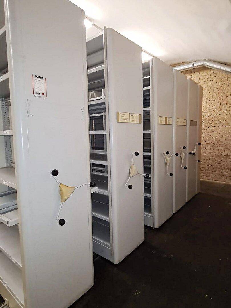 Nahaufnahme der mobilen Regalsysteme mit Kurbeln in einem Kellerraum.