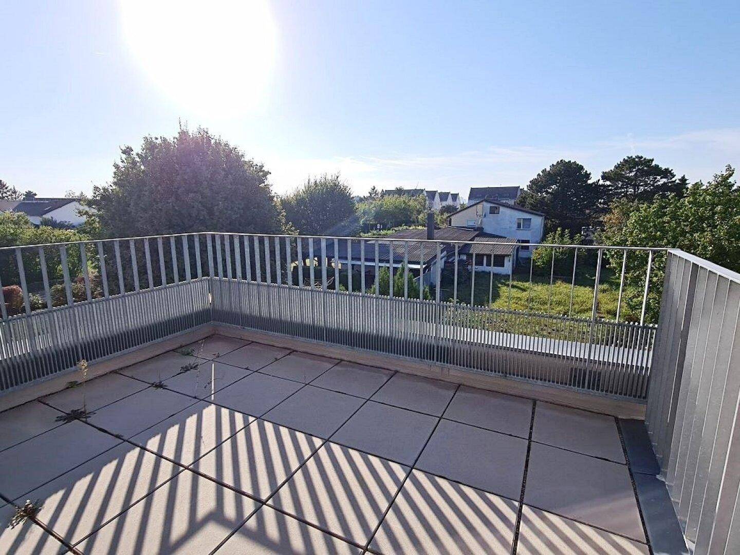 Geräumige Dachterrasse mit Fliesenboden und weitem Blick über die umliegende Wohngegend.