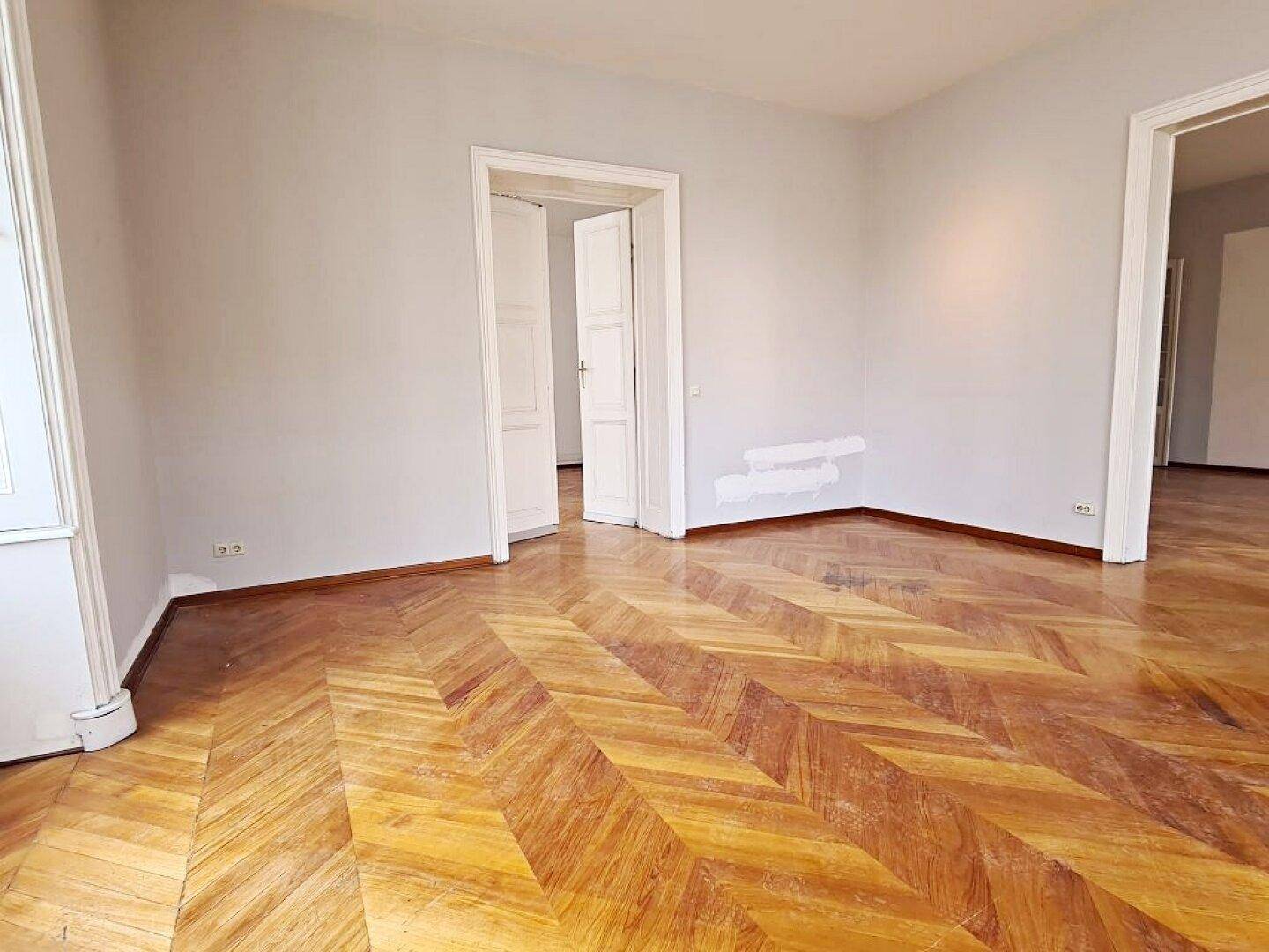 Geräumiges Zimmer mit klassischem Fischgrätparkett und hellen Wänden, bereit zur individuellen Gestaltung.