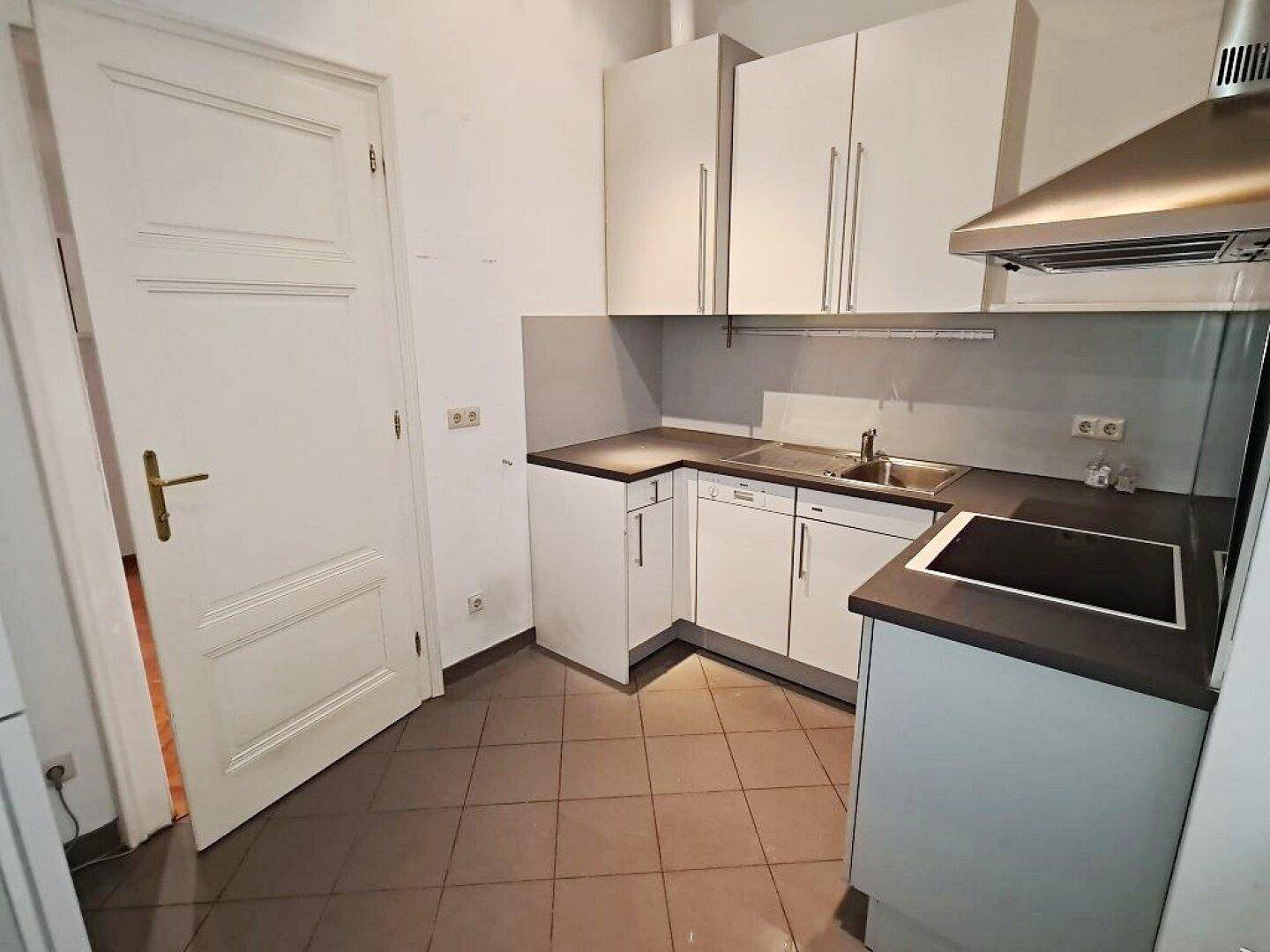Funktionale Küche mit weißen Schränken, Induktionskochfeld und Fliesenboden, ideal für den täglichen Gebrauch.