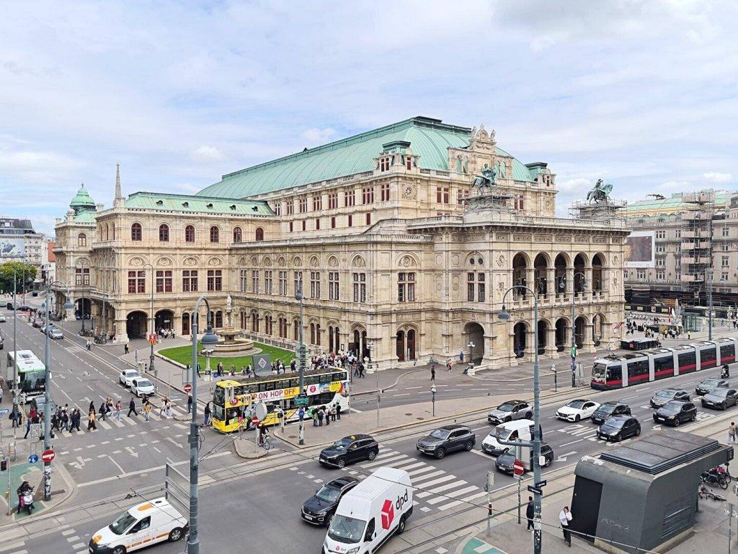 Panoramablick auf ein historisches Gebäude und die belebte Stadtlandschaft mit Verkehr.