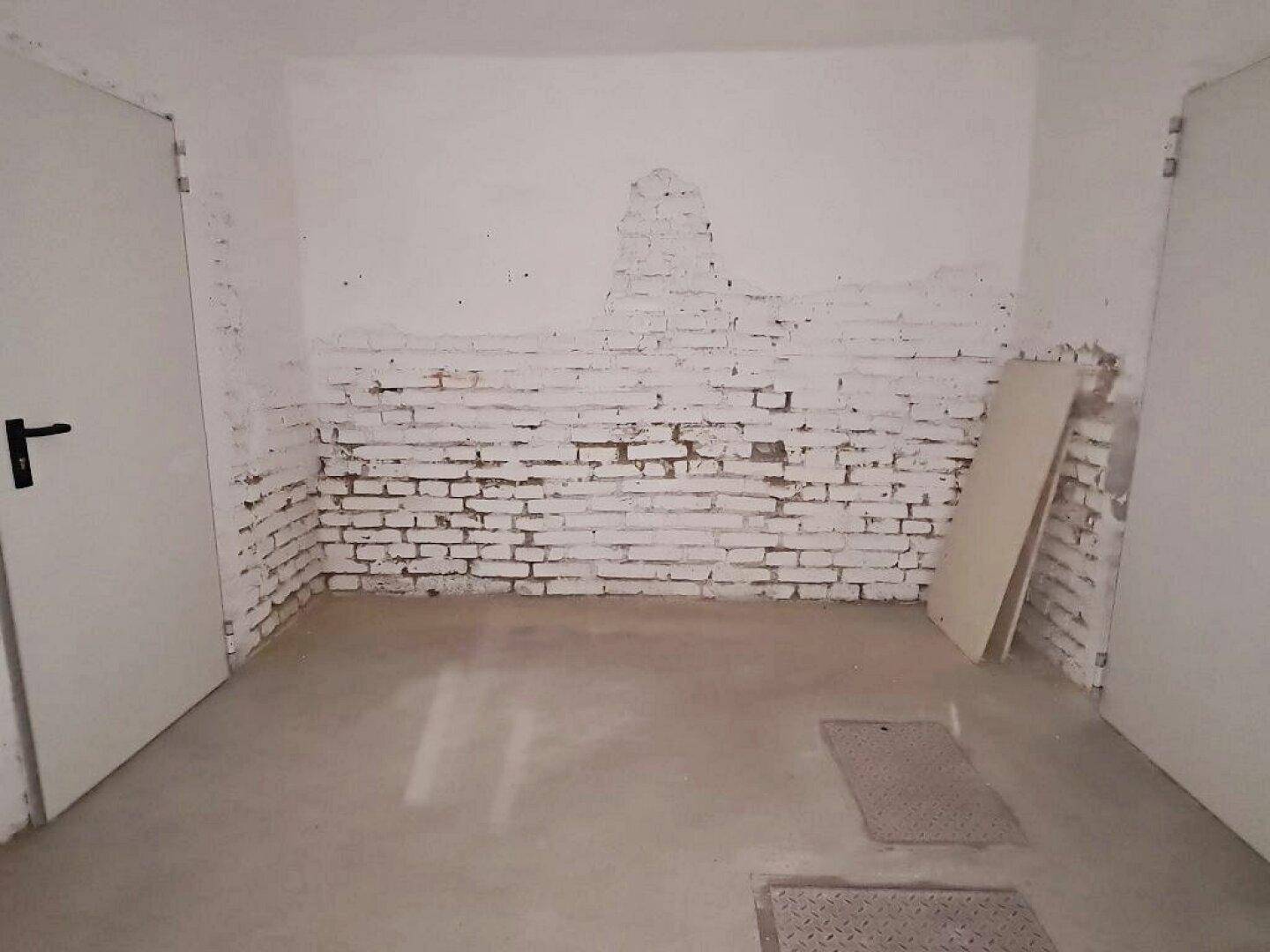 Einfacher Kellerraum mit freigelegten Ziegelwänden, die teilweise weiß gestrichen sind, und einem robusten Betonboden.