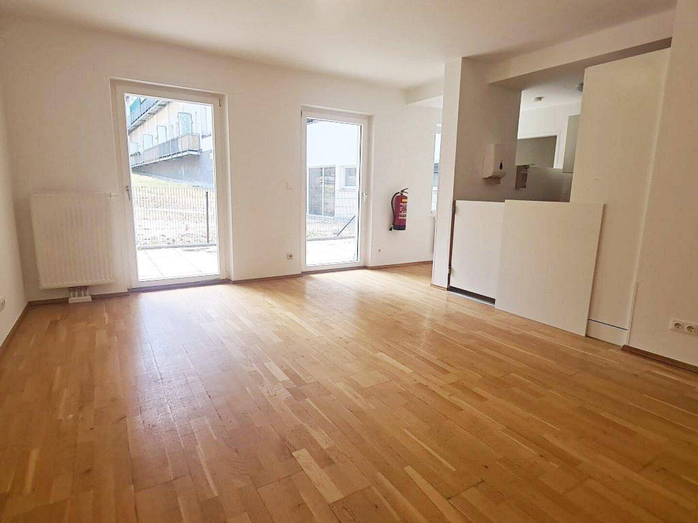 Helles Zimmer mit Parkettboden und Zugang zu einem Außenbereich, ideal als Wohnzimmer nutzbar.