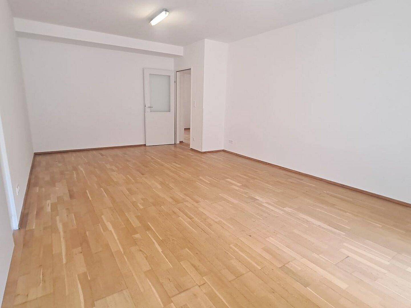 Heller Wohnraum mit Parkettboden und Zugang zu weiteren Zimmern, bietet vielseitige Nutzungsmöglichkeiten.