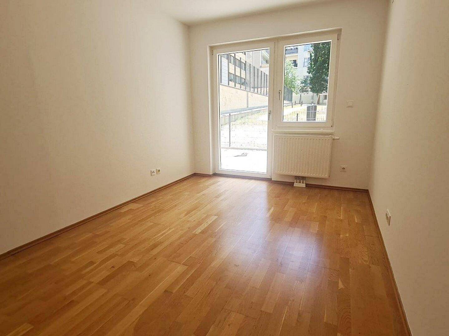 Ruhiges Zimmer mit Parkett und Zugang zum Außenbereich, ideal als Schlaf- oder Arbeitszimmer.