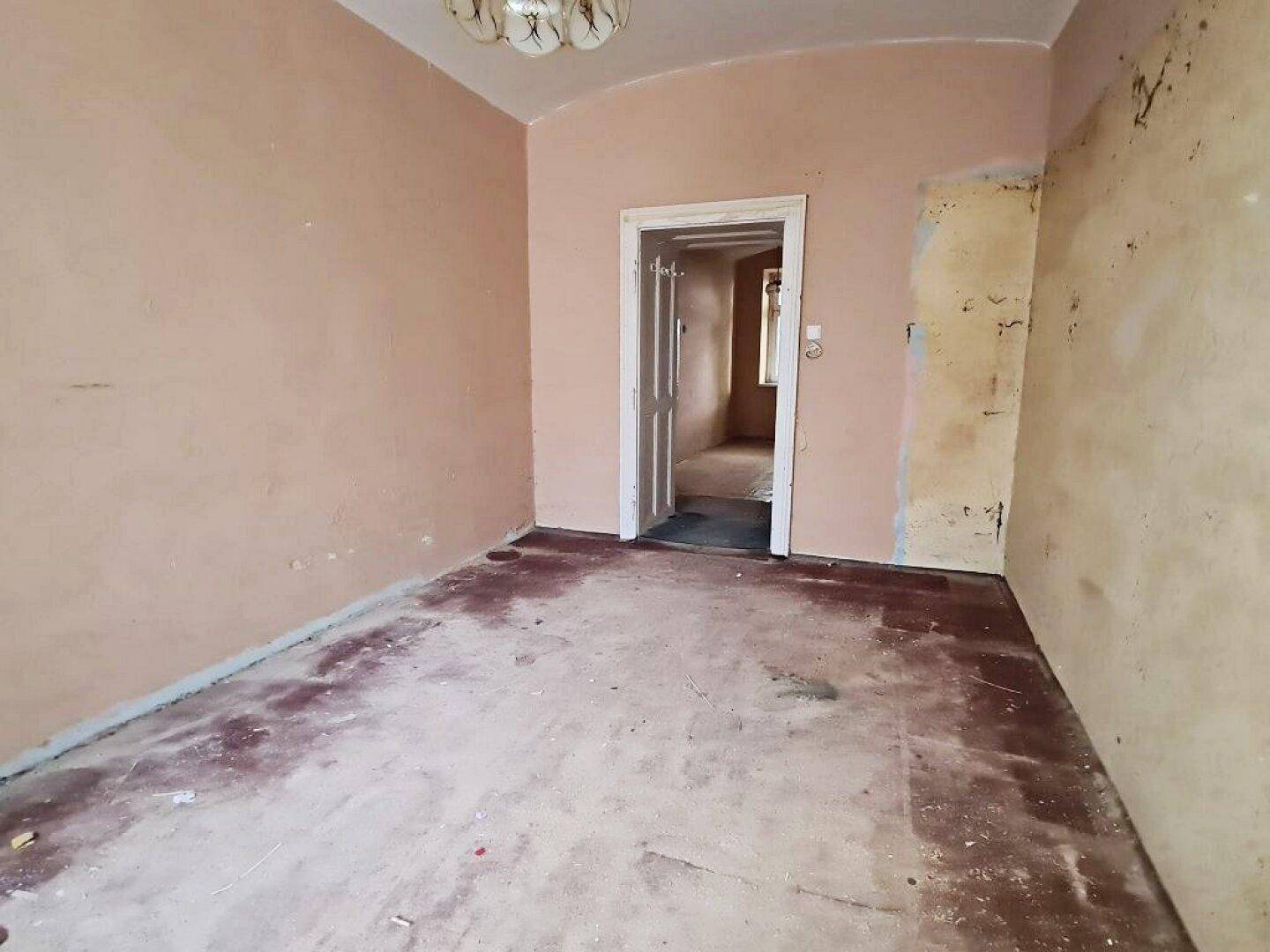 Leeres Zimmer mit Türrahmen und abgenutzten Wänden, bereit für eine umfassende Renovierung.