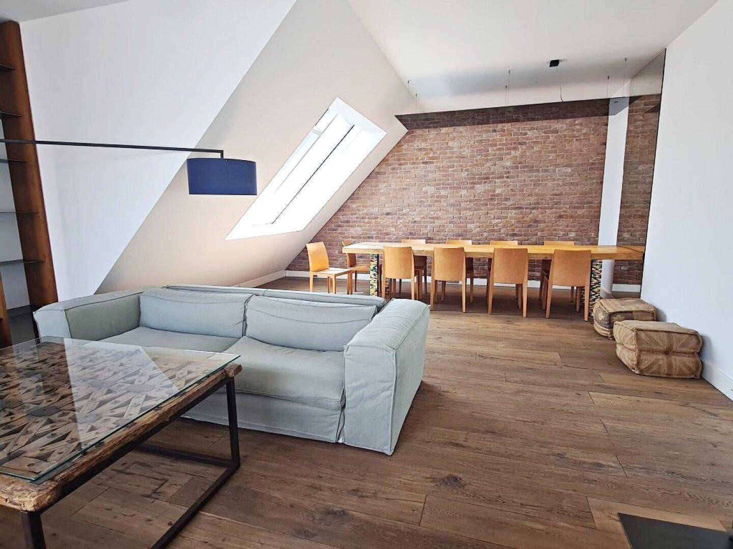 Essbereich mit großem Holztisch, Stühlen und Dachfenstern unter einer schrägen Decke.