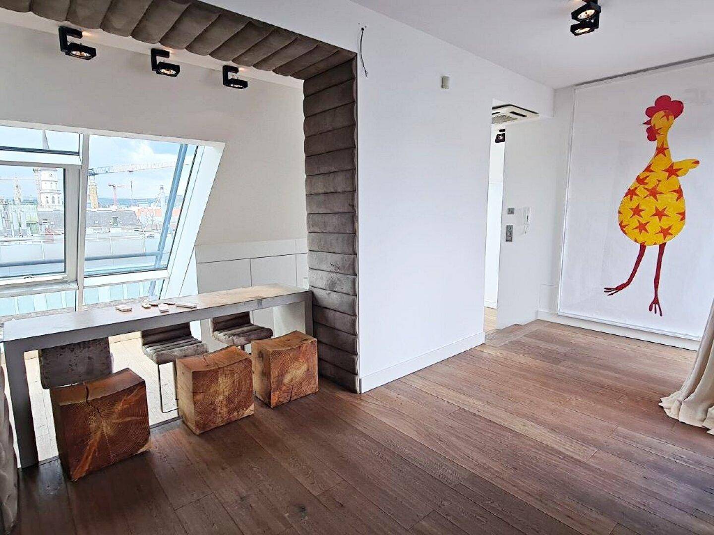 Heller Bereich mit Holzboden, Dachfenstern und einer Theke mit Hockern.