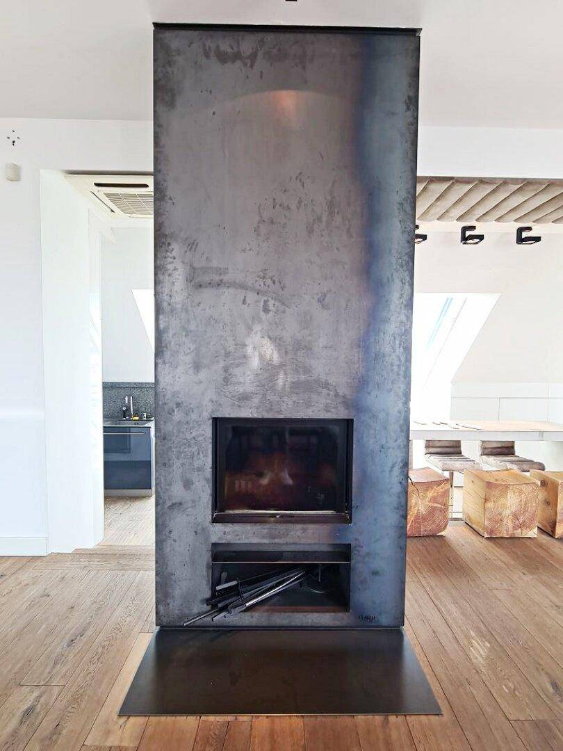 Moderner Kamin als Raumteiler im offenen Wohnbereich mit Holzboden.