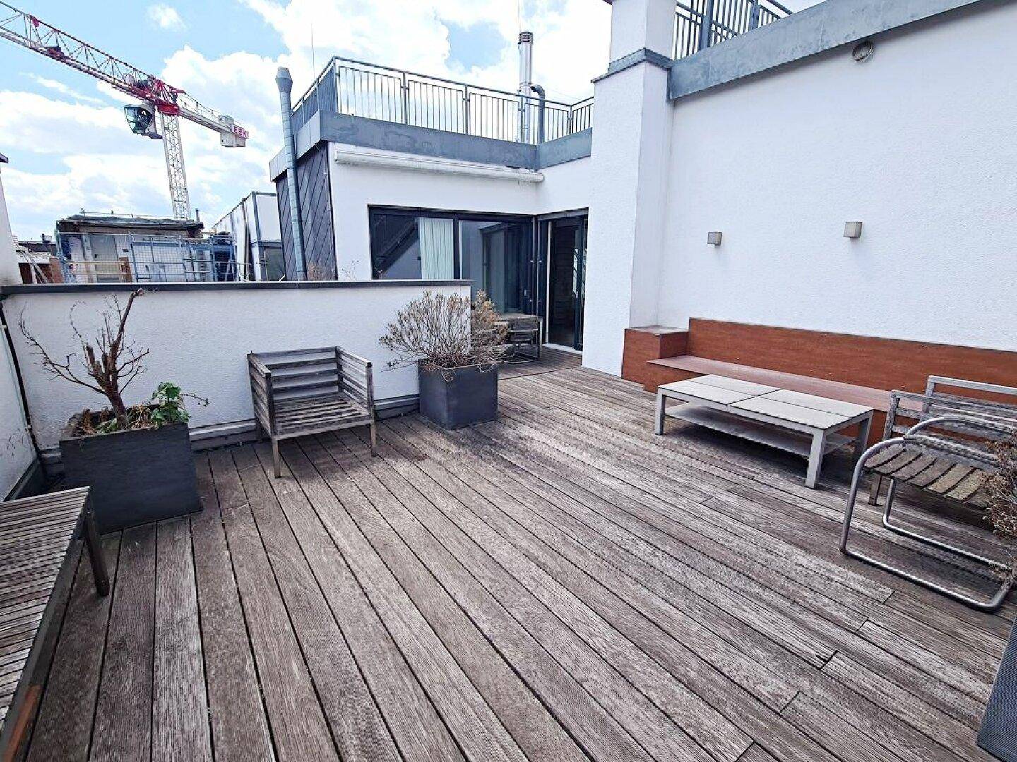 Weitläufige Dachterrasse mit Holzdeck, Sitzgelegenheiten und Blick auf die Umgebung.