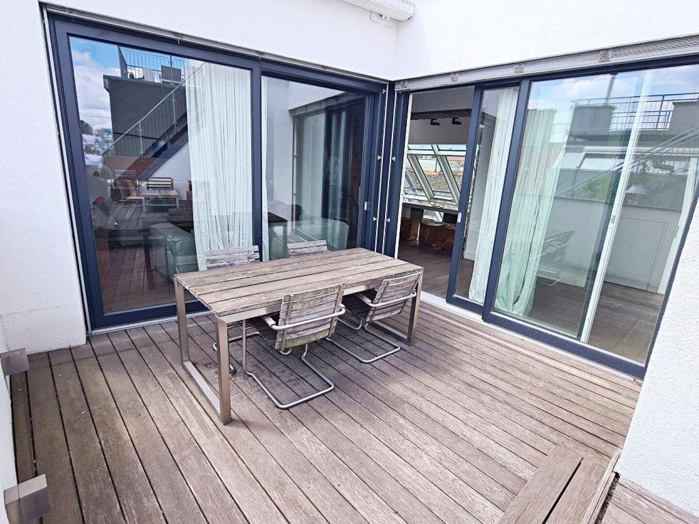 Essbereich im Freien auf der Dachterrasse mit Holztisch und Stühlen.