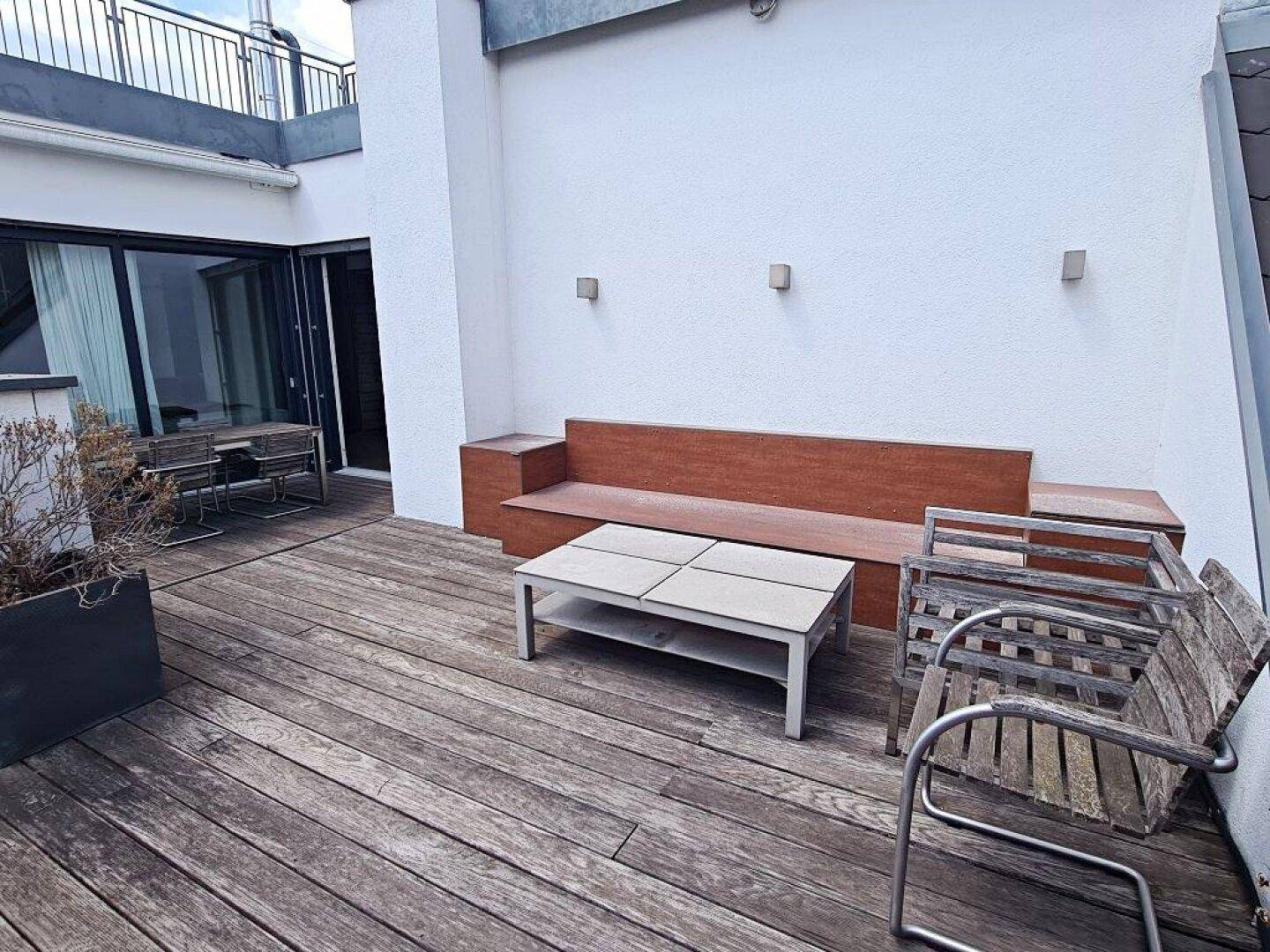 Dachterrasse mit Holzdeck, eingebauter Sitzbank und modernen Außenleuchten.