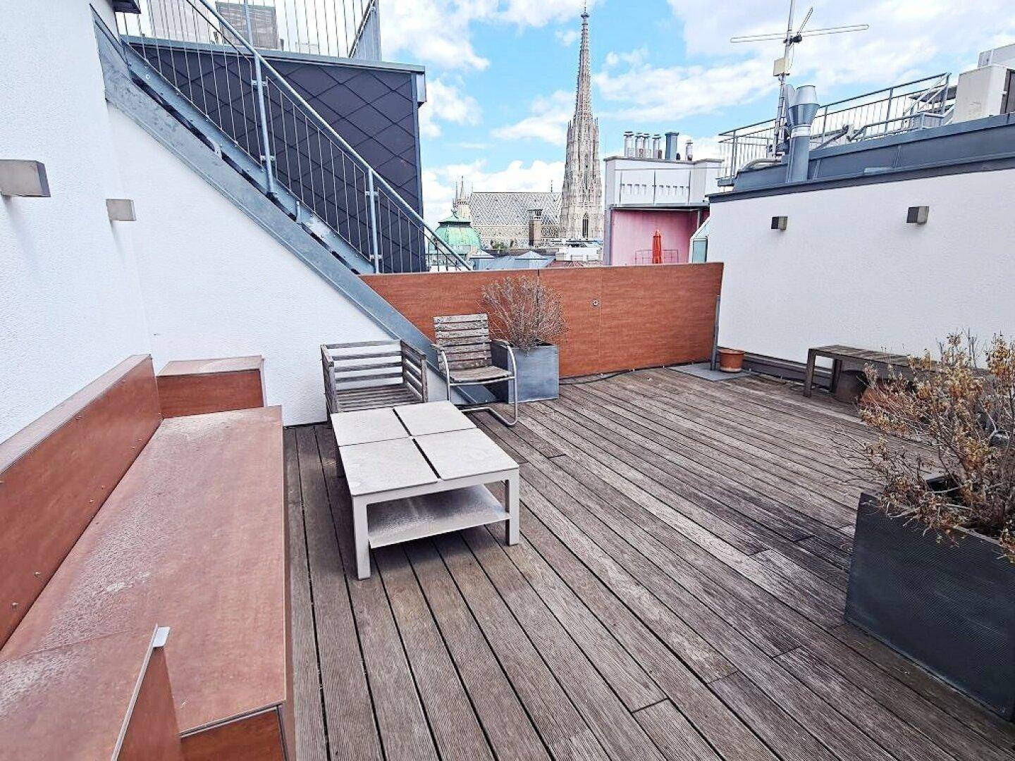 Dachterrasse mit Sitzgelegenheiten und Blick auf die Stadt und den Stephansdom.