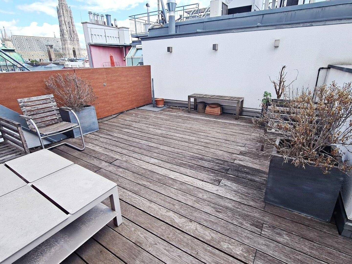 Geräumige Dachterrasse mit Holzdeck und Blick auf die Stadtkulisse.