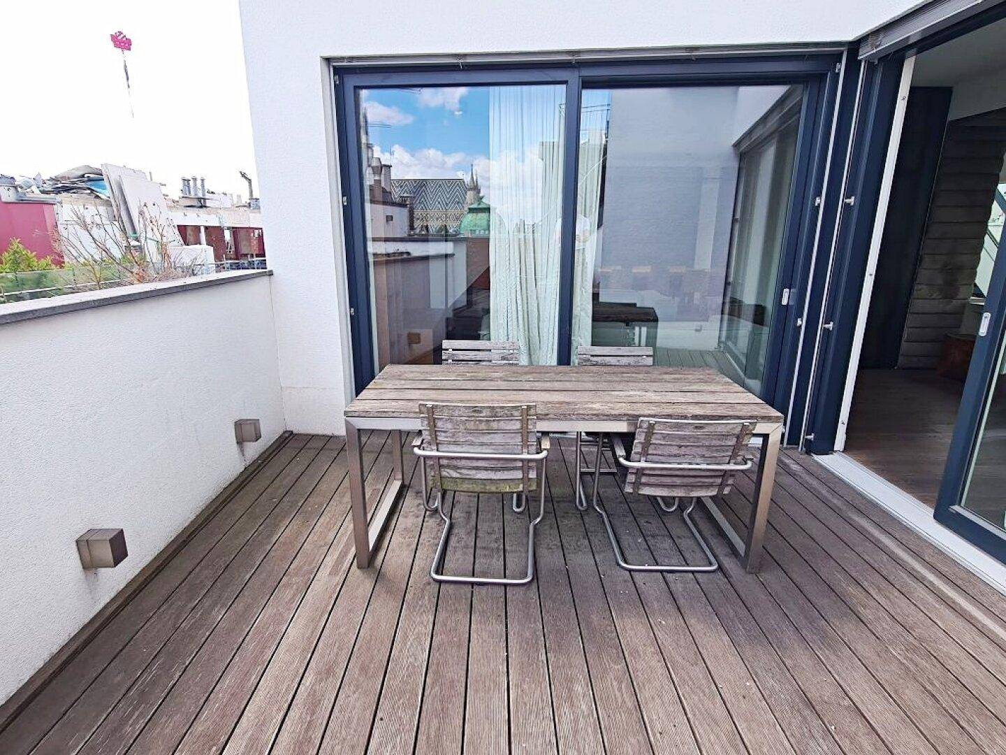 Essbereich im Freien auf der Dachterrasse mit Holztisch und Stühlen.