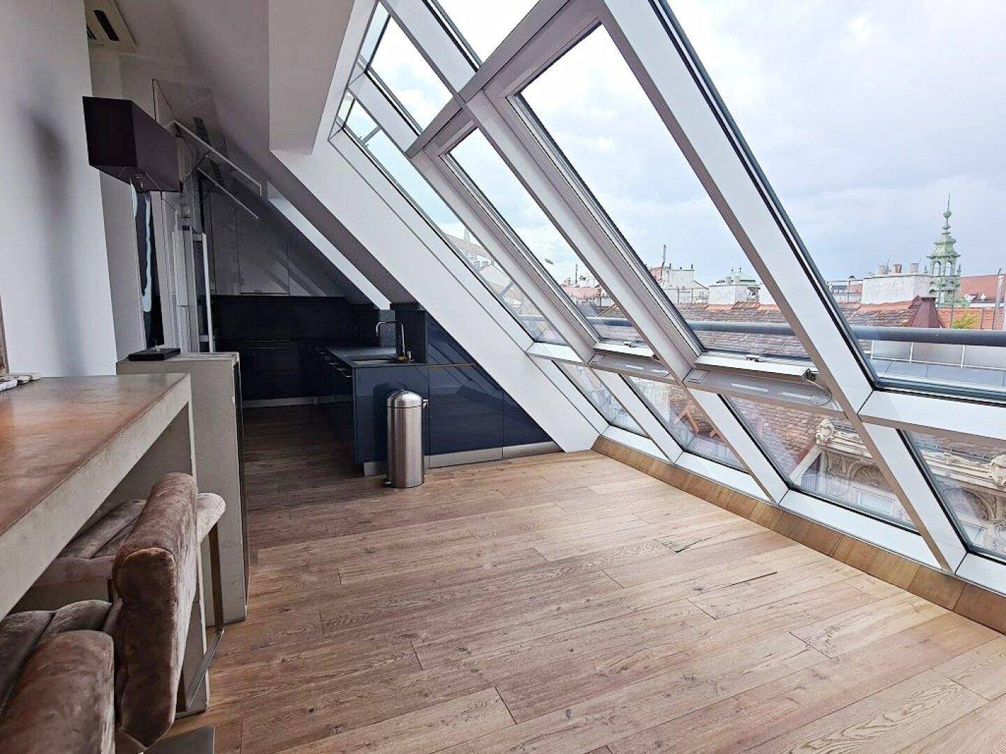Moderne Küche mit Dachschrägen, großen Fenstern und Holzboden.