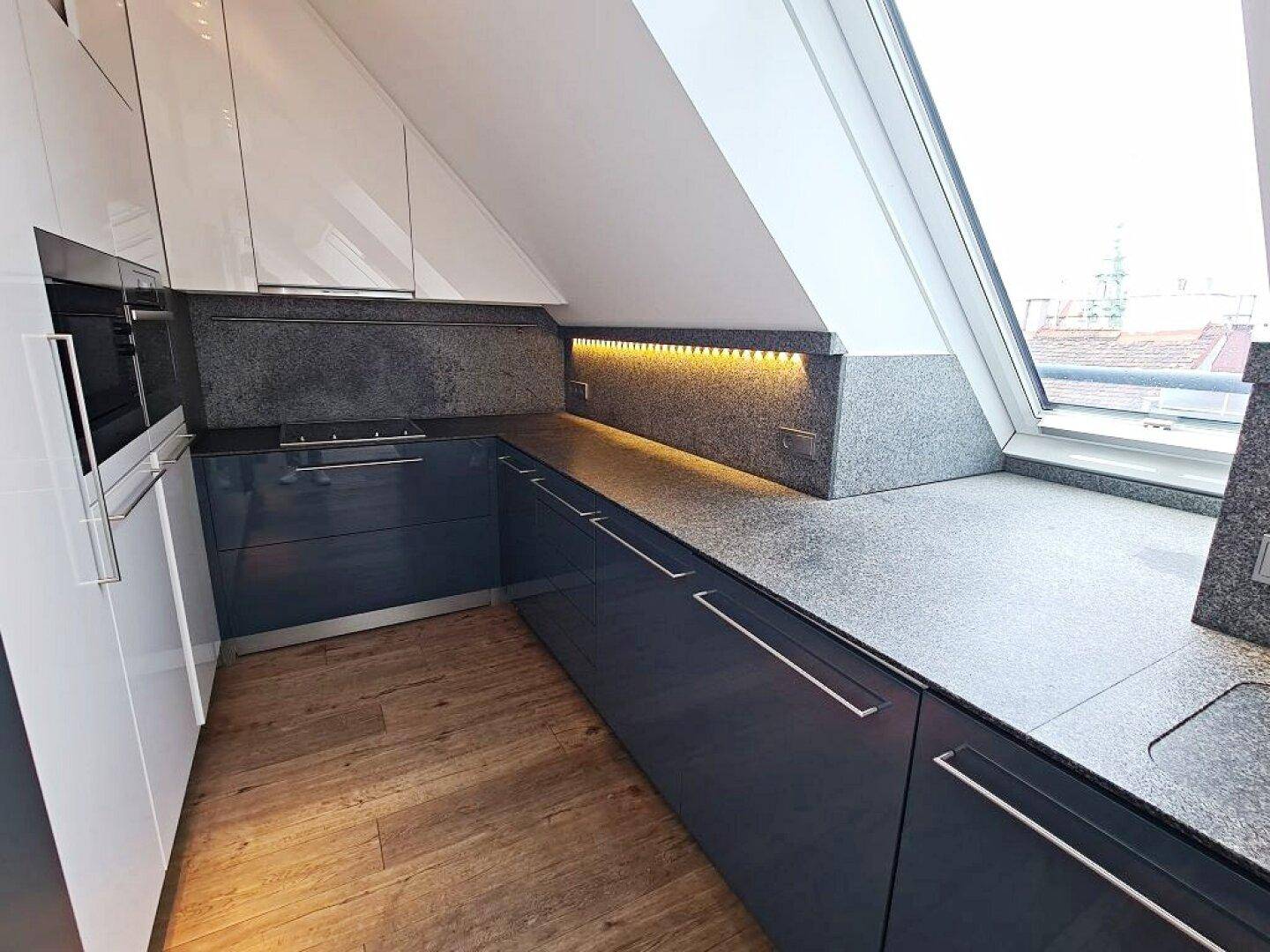 Helle Einbauküche mit grauen Fronten, Granitarbeitsplatten und Dachfenstern.