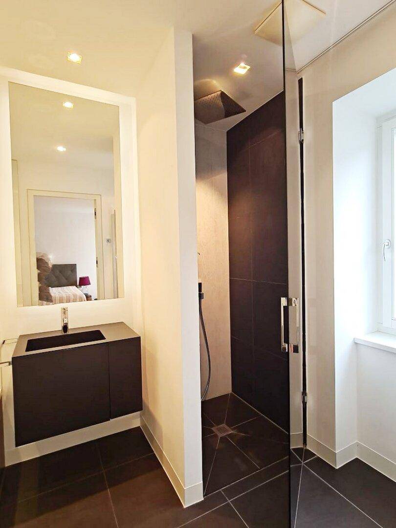 Modernes Badezimmer mit begehbarer Dusche, schwarzem Waschtisch und einem Fenster für Tageslicht.