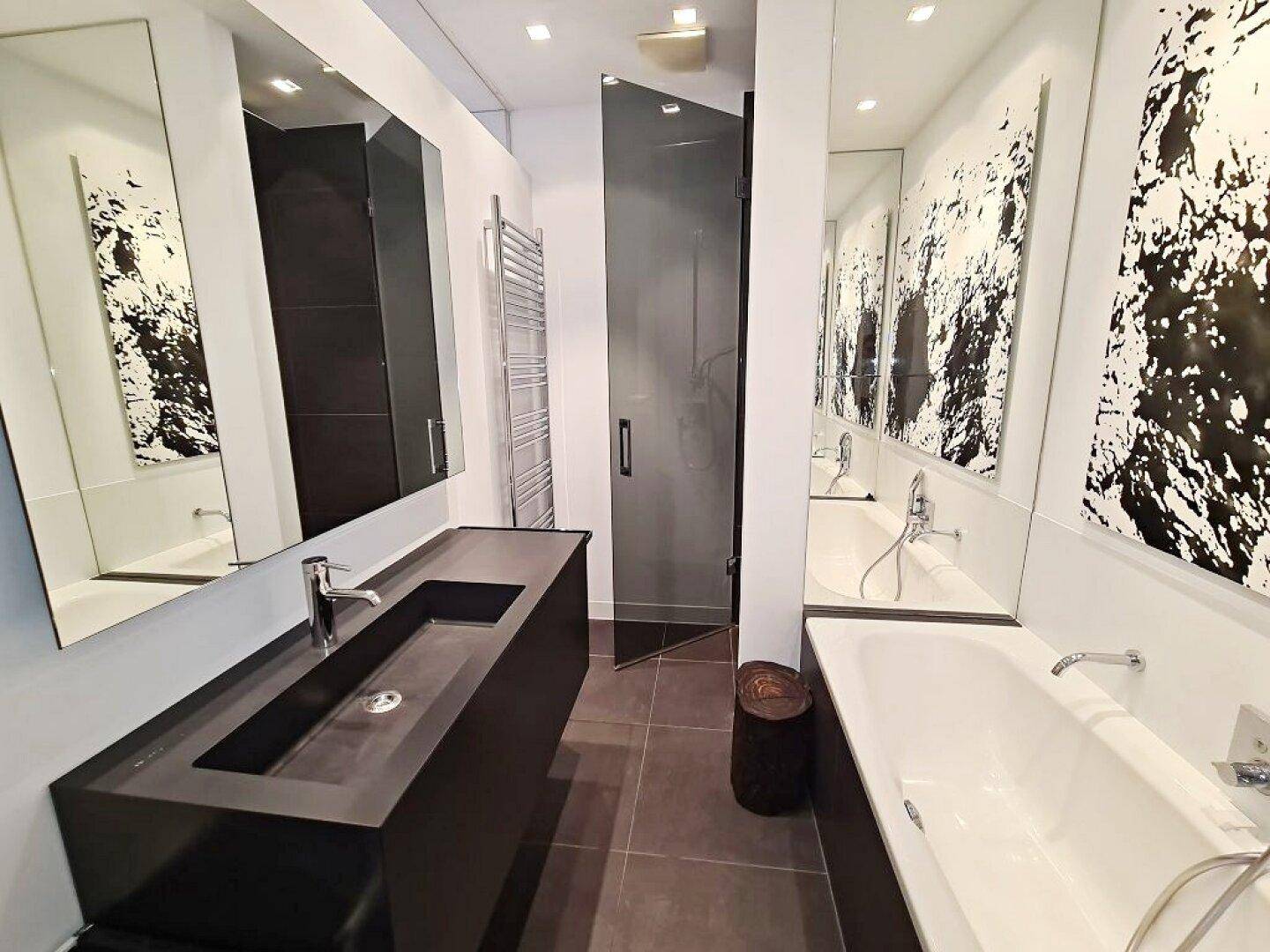 Modernes Badezimmer mit dunklem Waschtisch, Badewanne und separater Dusche, elegant gefliest.