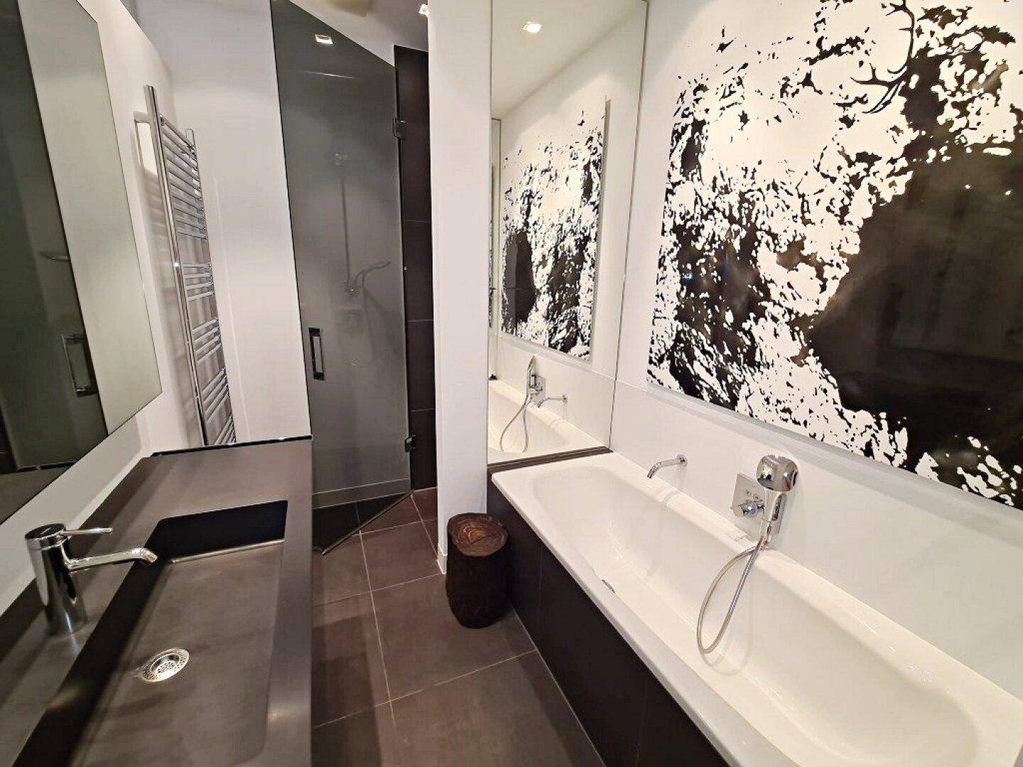 Elegantes Badezimmer mit Badewanne, großem Spiegel und moderner Duschkabine mit Glaswand.