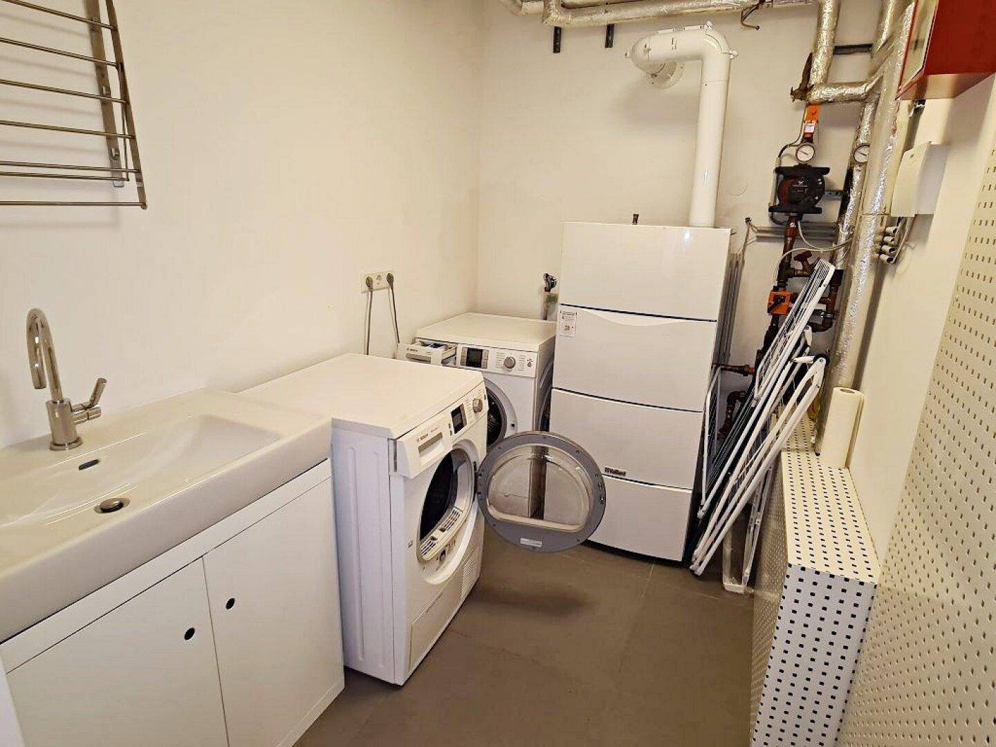 Praktischer Hauswirtschaftsraum mit Waschmaschine, Trockner und Spülbecken, ideal für den Alltag.