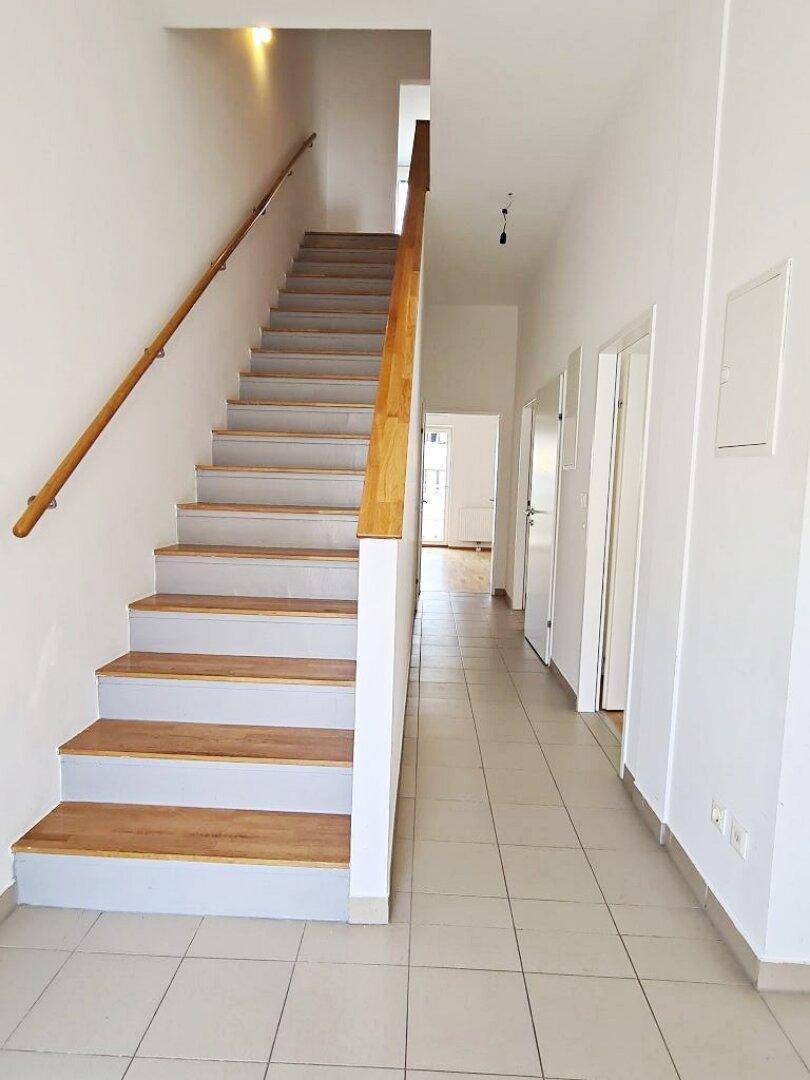 Heller Flur mit Treppe und Fliesenboden, der zu den oberen Etagen führt.