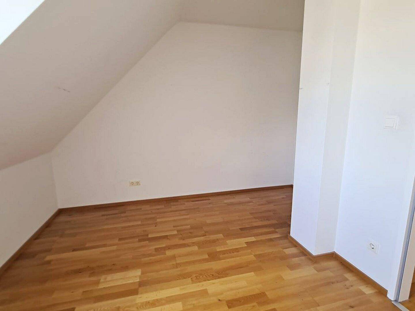 Geräumiges Dachzimmer mit Parkettboden und schrägen Wänden, bietet viel Potenzial.