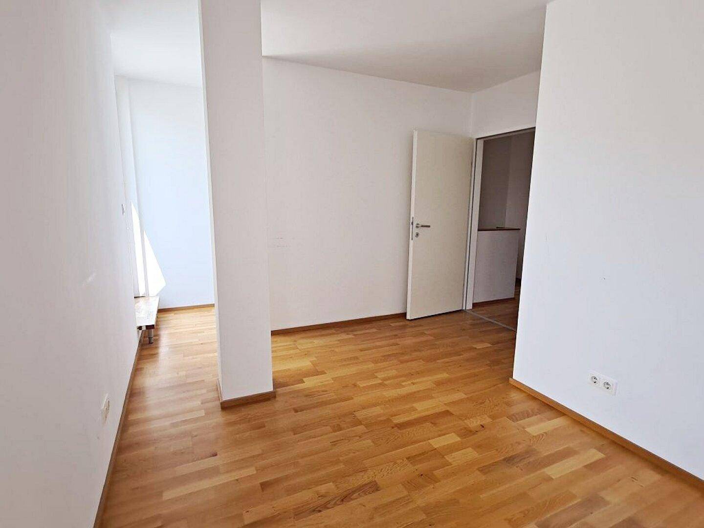 Geräumiges Zimmer mit hellem Parkettboden und weiß gestrichenen Wänden, bereit zur individuellen Gestaltung.