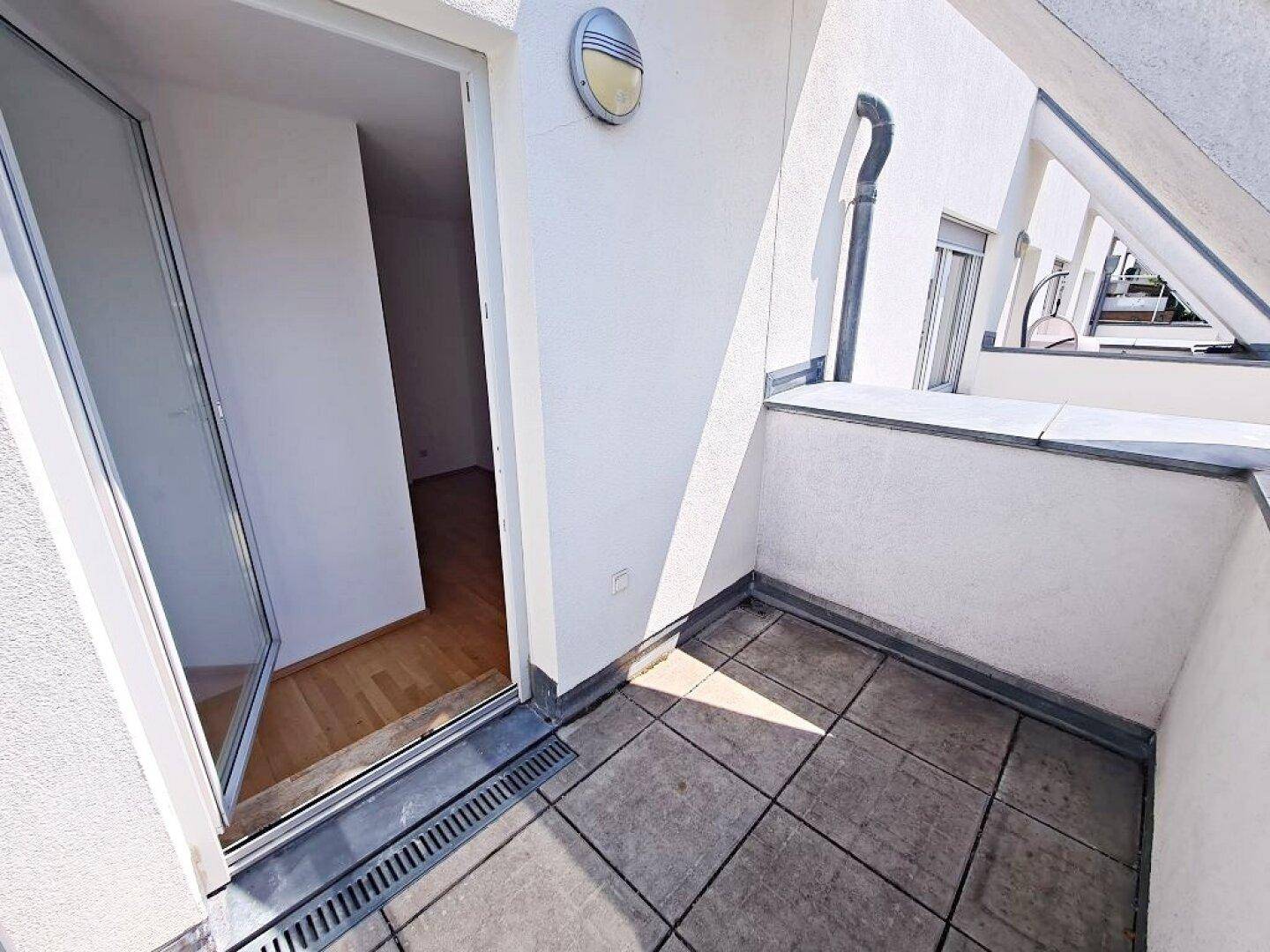 Heller Balkon mit Fliesenboden und direktem Zugang zum Innenbereich der Wohnung.