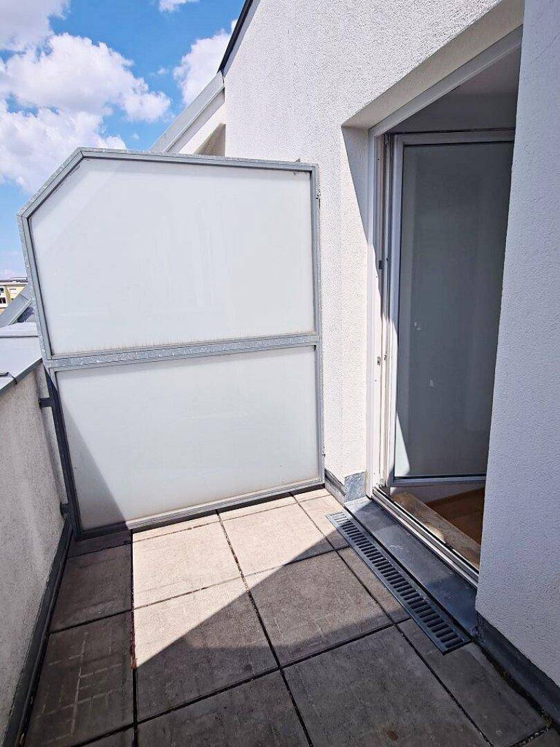 Zugang zu einem kleinen Balkon mit Fliesenboden und Metallgeländer, ideal für frische Luft.